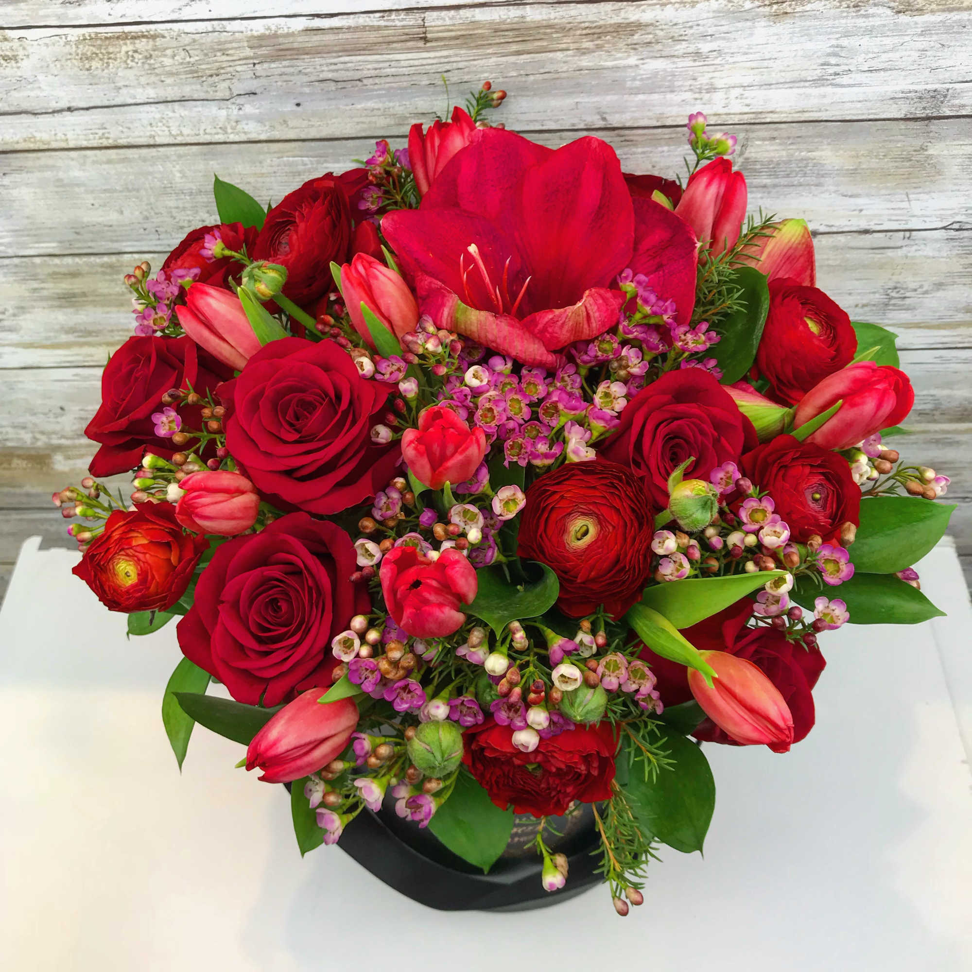 A pleasing combination of red  roses , red Ranunculus, red tulips