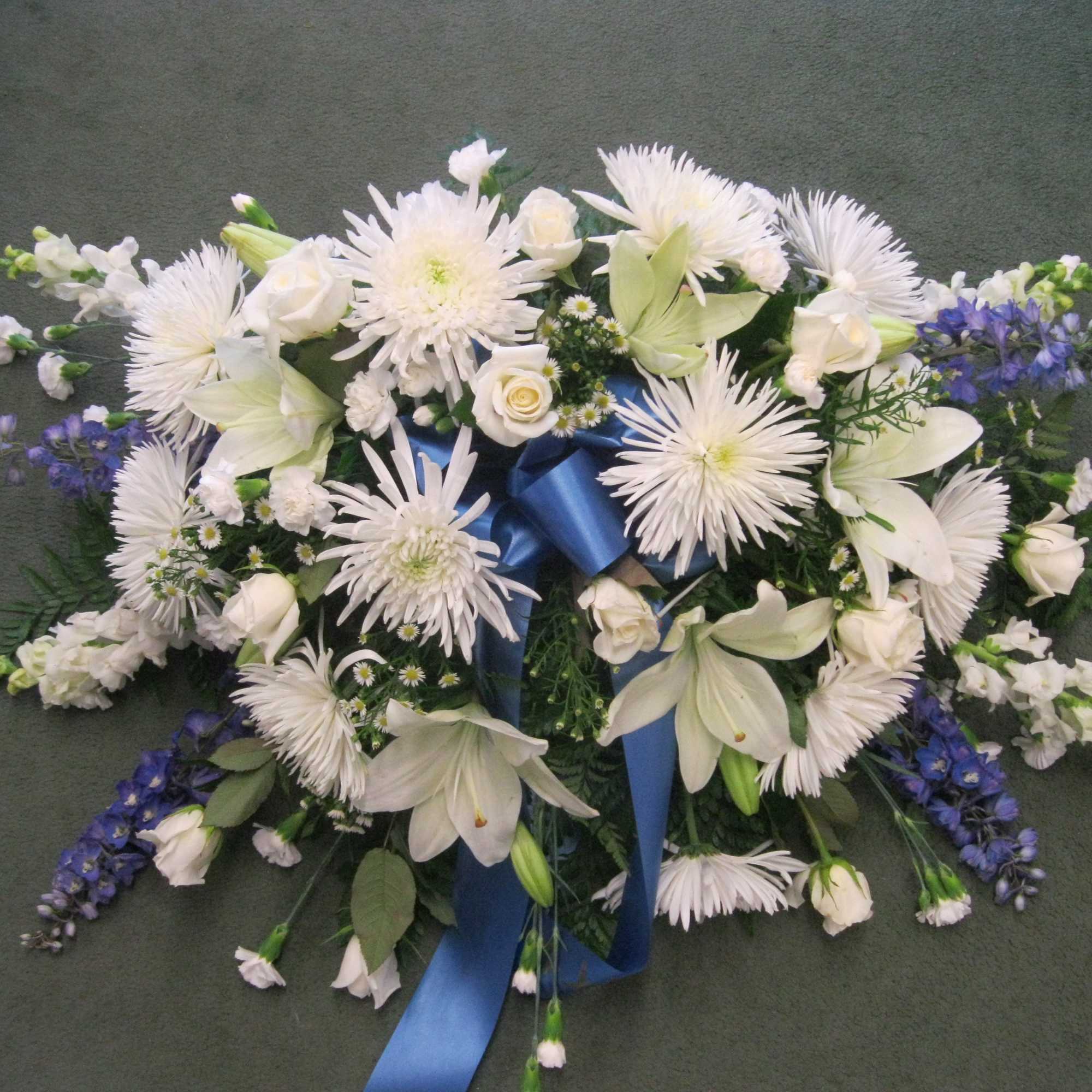 This casket cover is desinged with a variety ofwhite and blue flowers This casket cover is desinged with a variety ofwhite and blue flowers