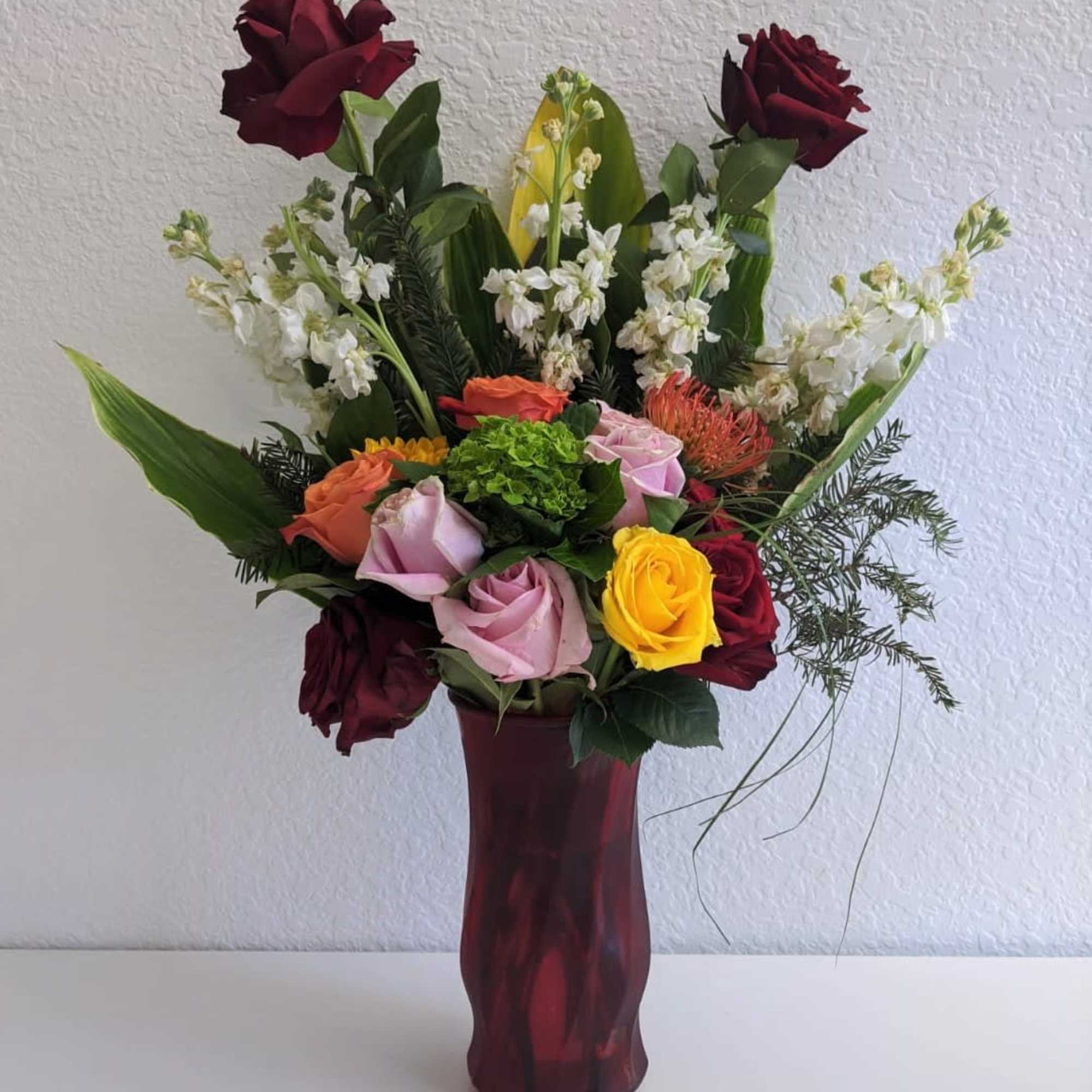 A wonderful combination of roses and flowers in a cute red vase