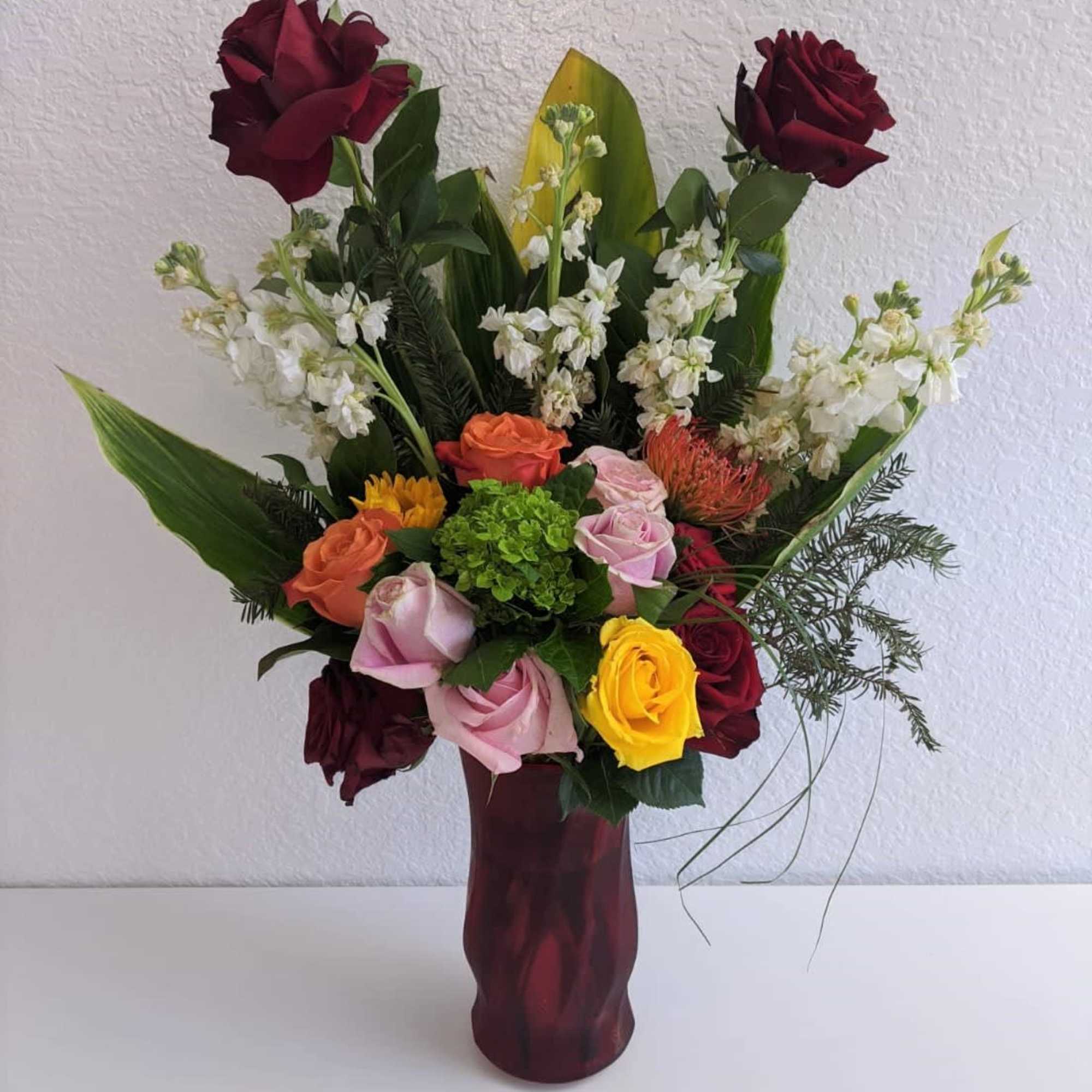 A wonderful combination of roses and flowers in a cute red vase