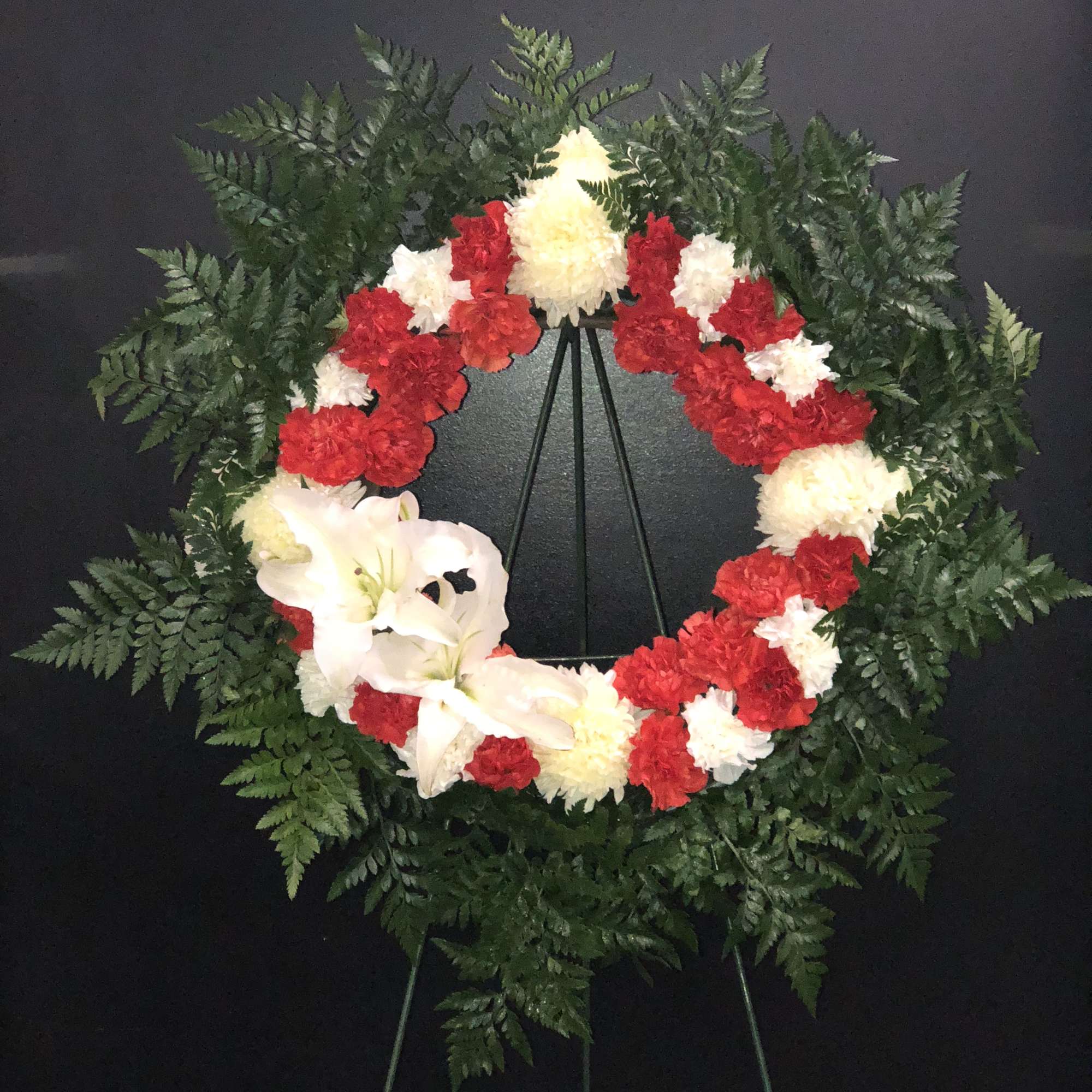 The circle of carnations with red and white with a white ribbon.