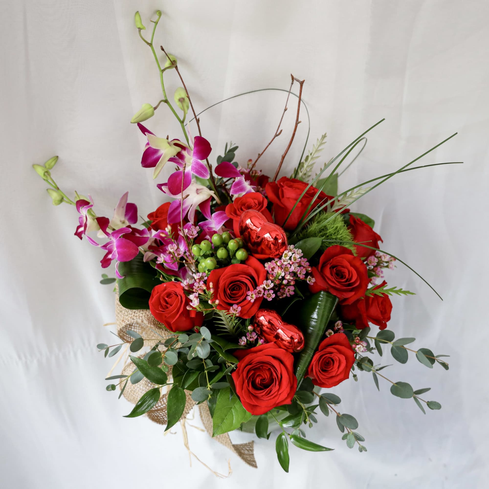 This Valentine&#039;s Day arrangement consists of a dozen red roses, orchids and