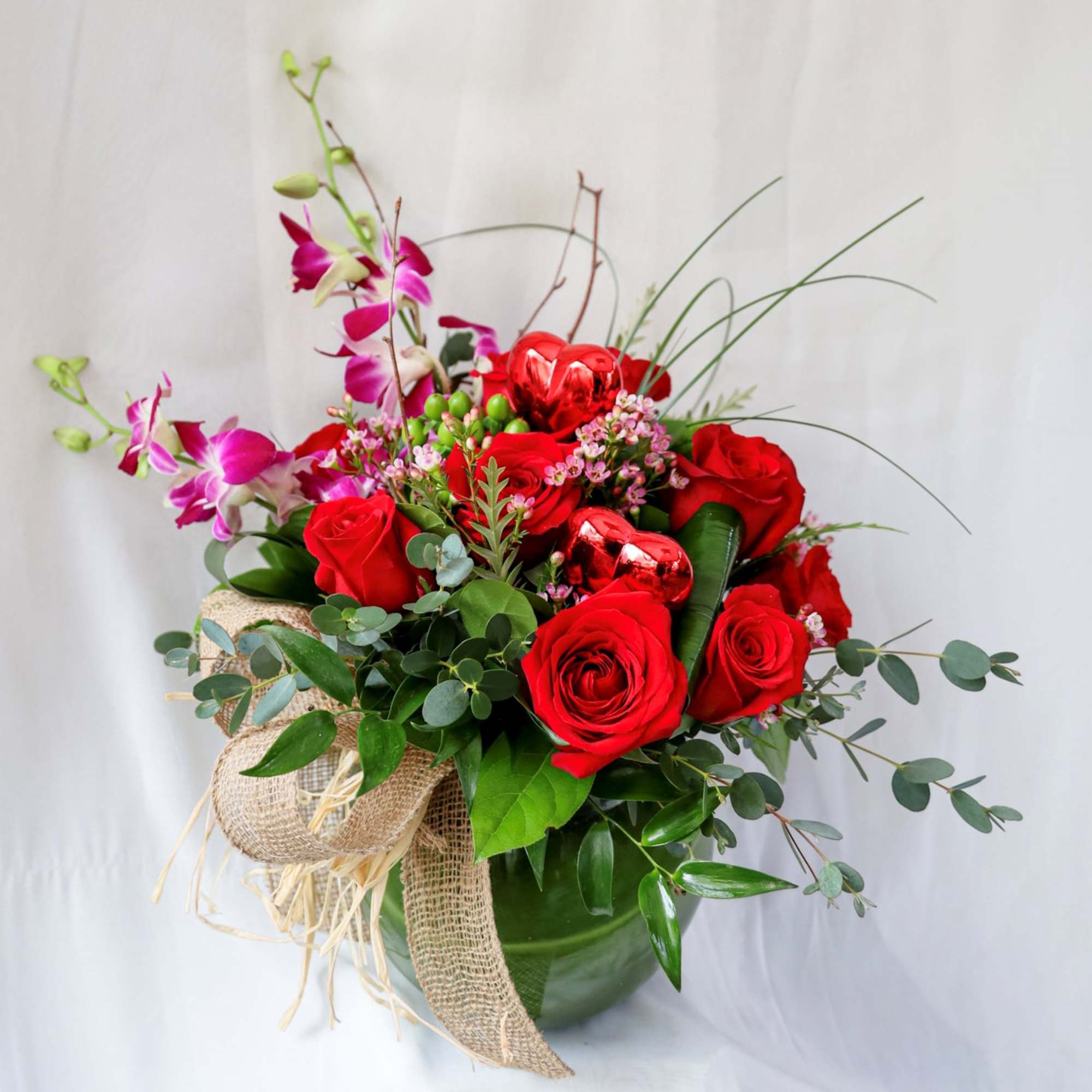 This Valentine&#039;s Day arrangement consists of a dozen red roses, orchids and