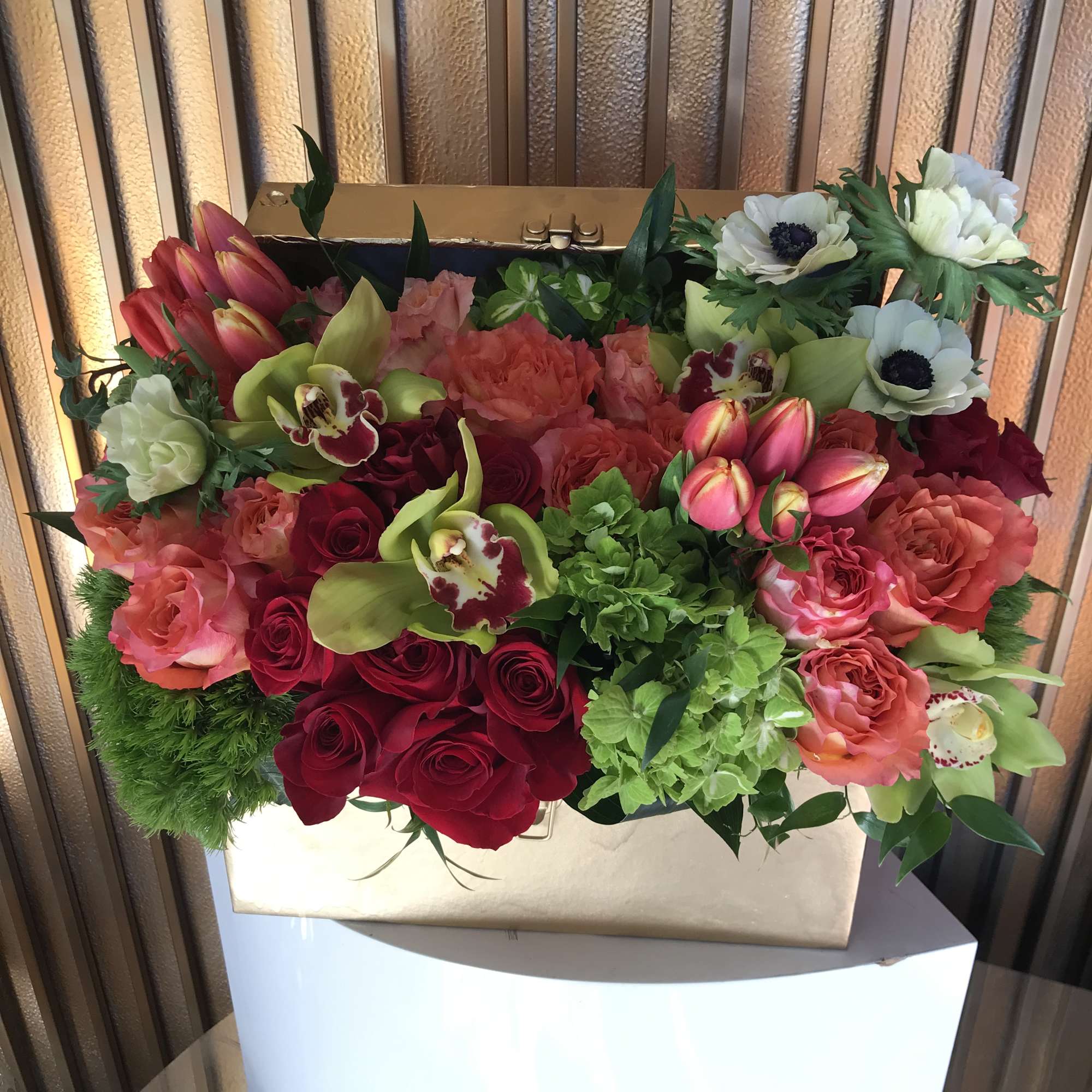 Designer arrangement of unique roses and tulips in a golden chest. 