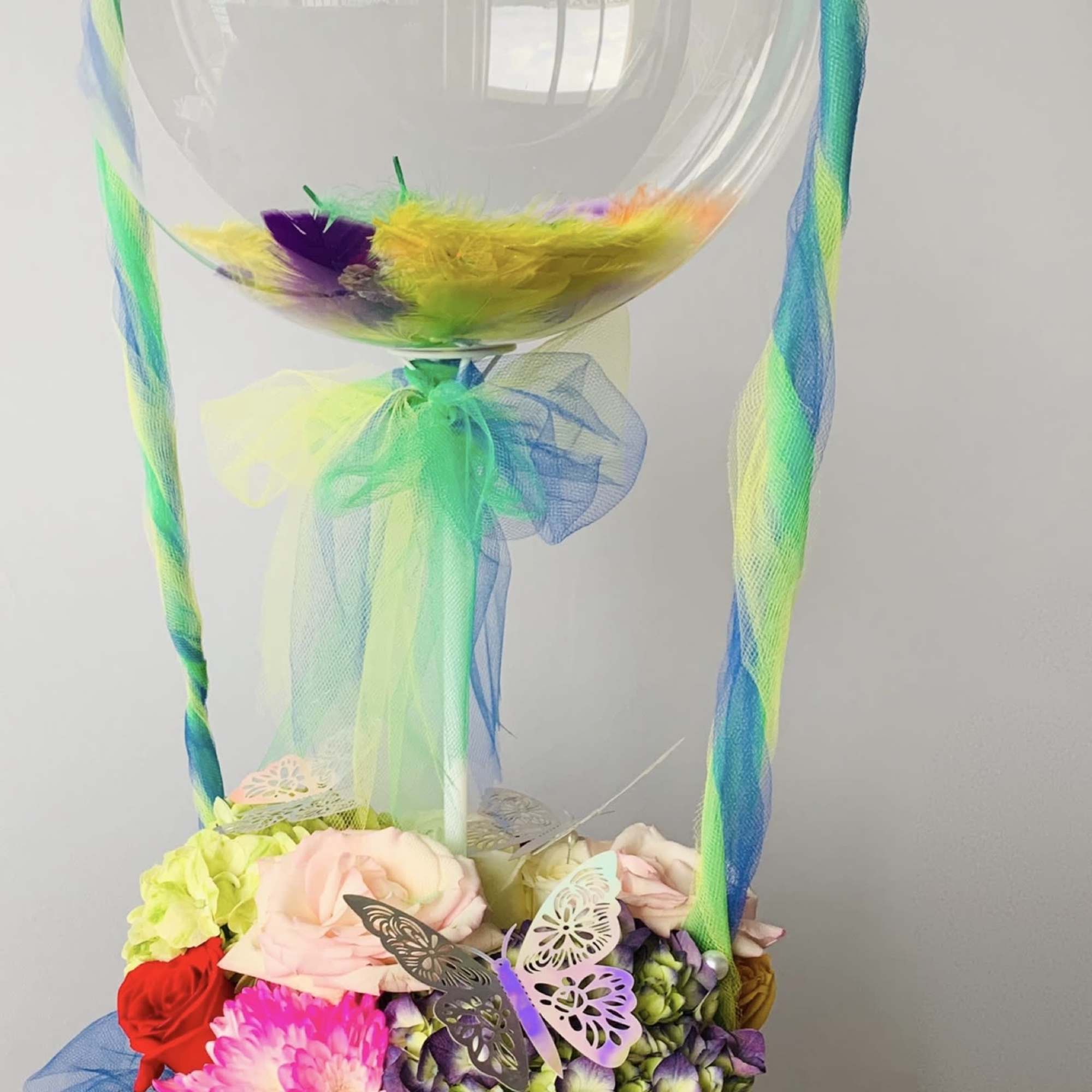 Fresh bright color  flower arrangement with fathers inside the bubble balloon.