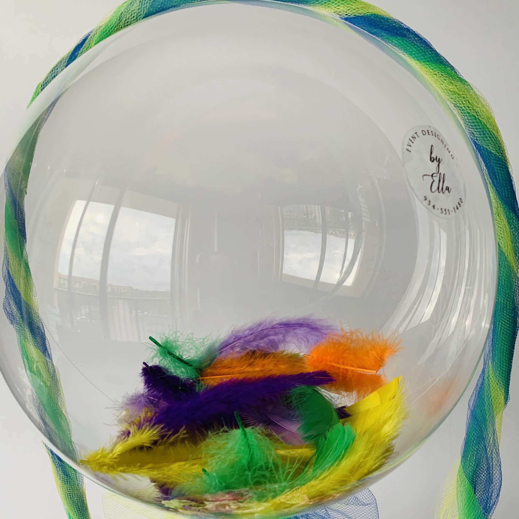 Fresh bright color  flower arrangement with fathers inside the bubble balloon.