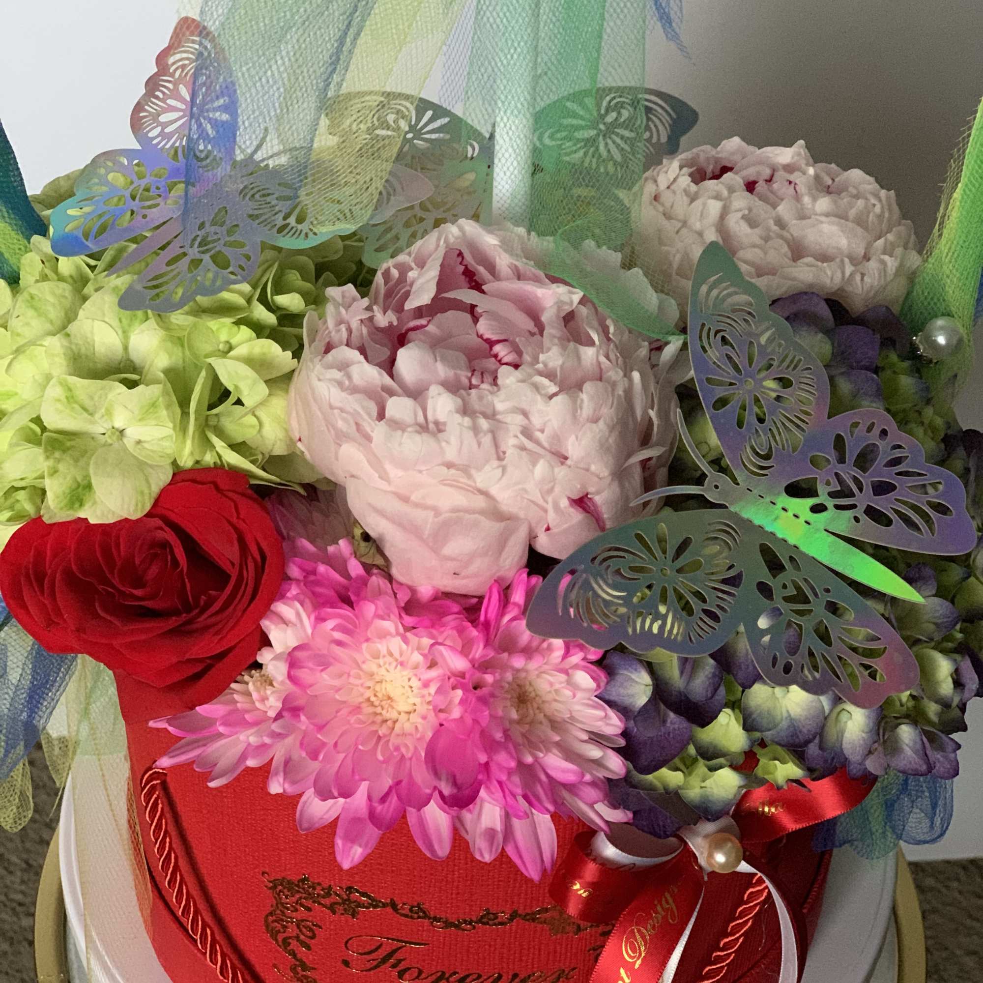 Fresh bright color  flower arrangement with fathers inside the bubble balloon.