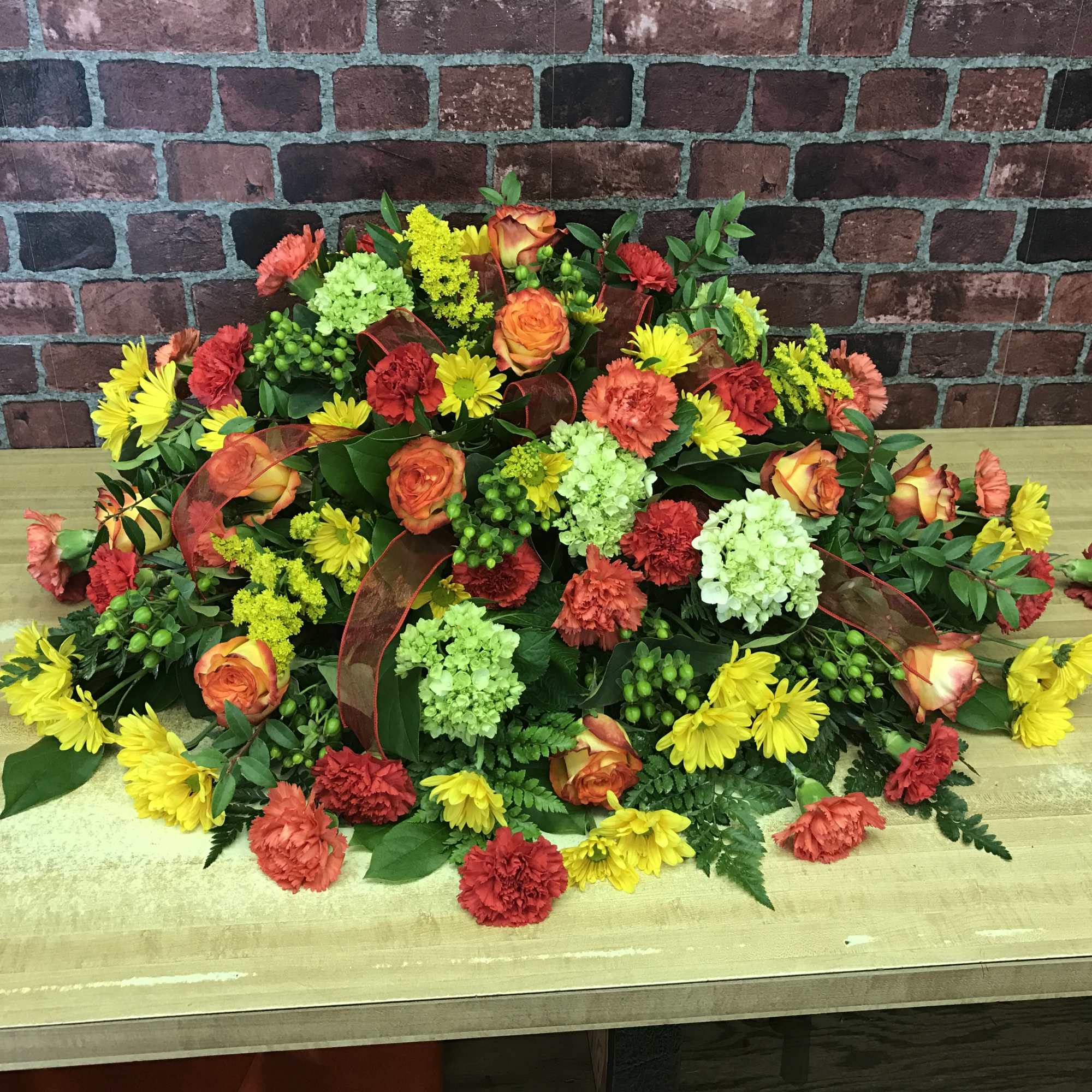 Beautiful spray perfectly designed for the top of a casket. Greens, yellows Beautiful spray perfectly designed for the top of a casket. Greens, yellows