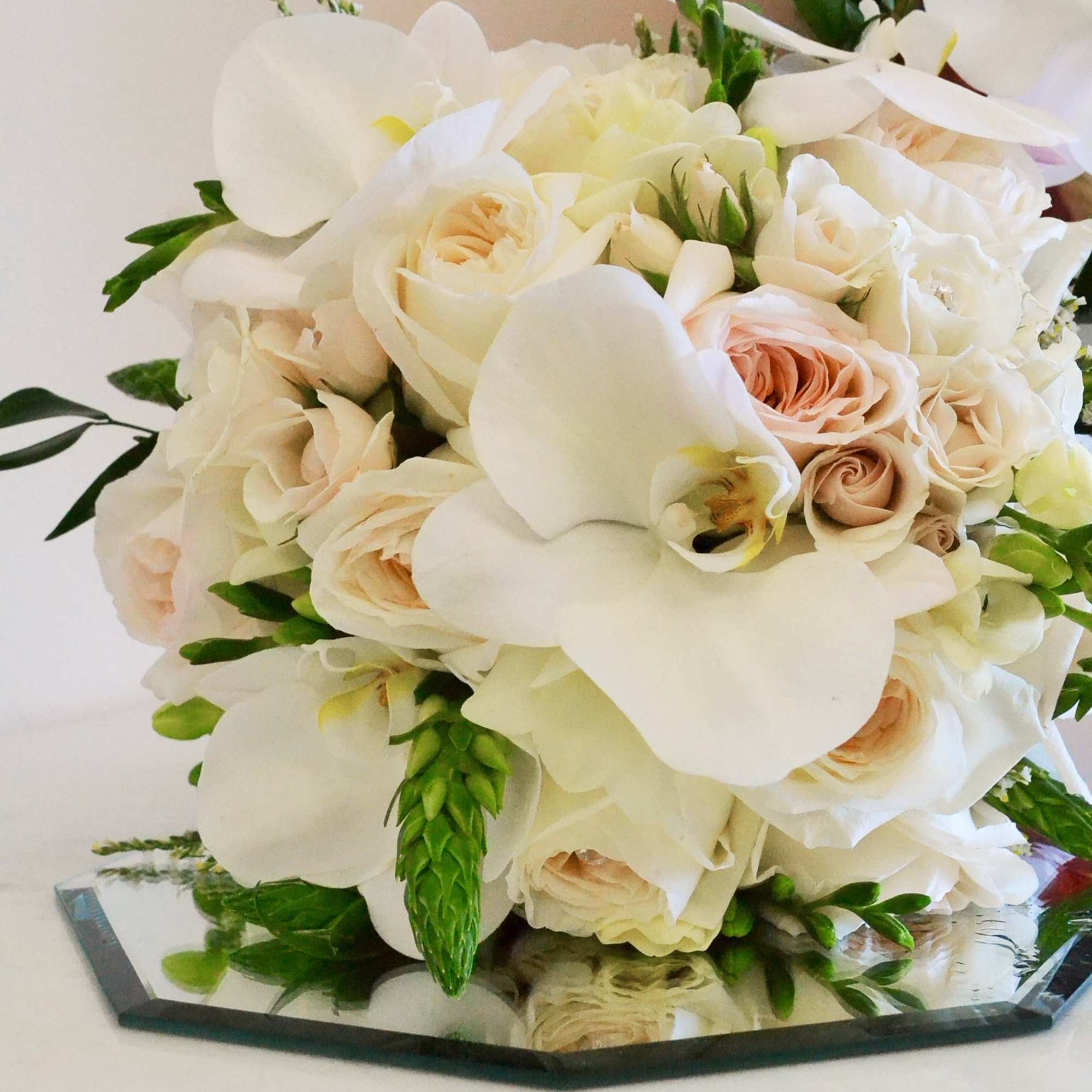 beautiful hand wrapped bouquet with garden roses and orchids.