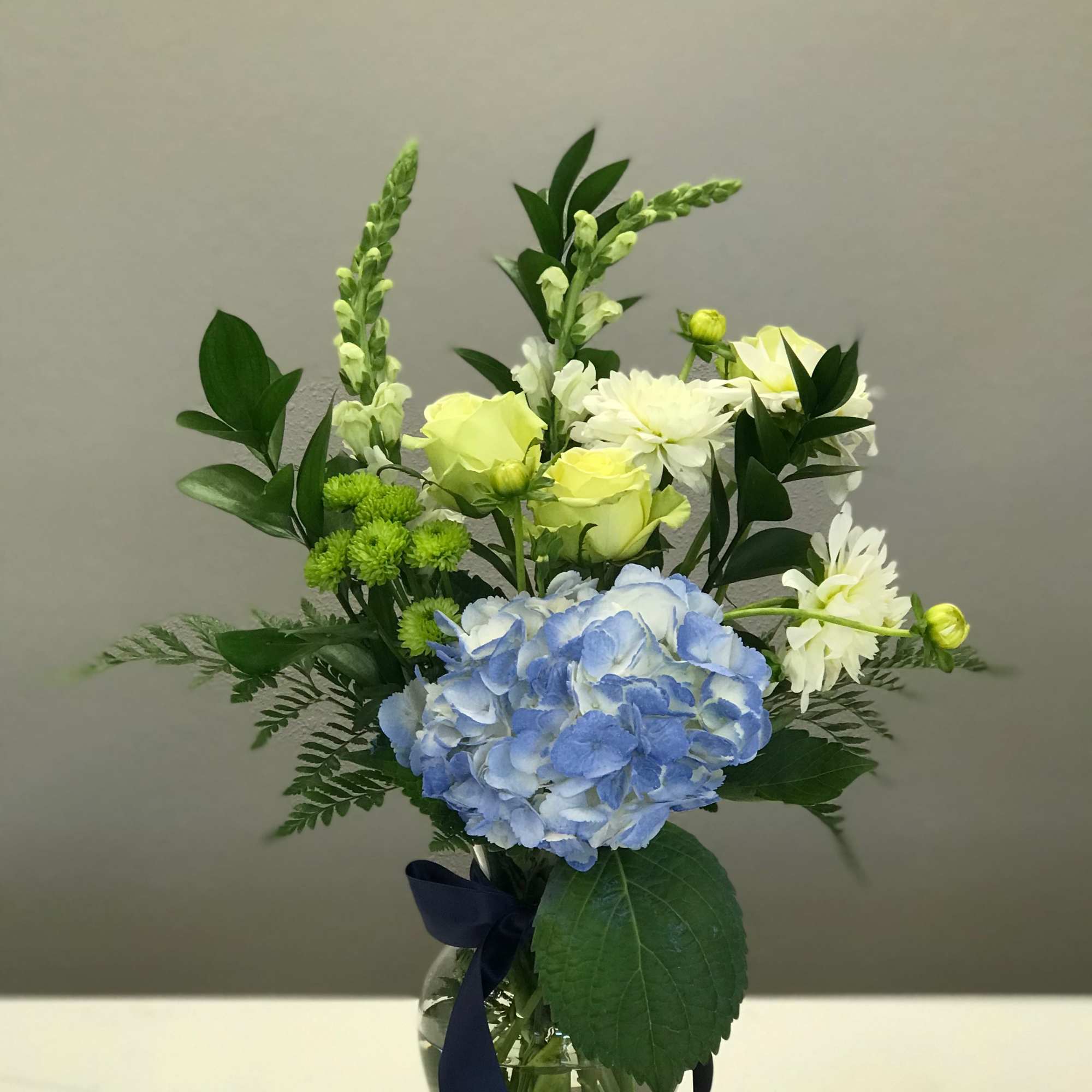 Shades of green and ivory float above a center stage blue hydrangea.