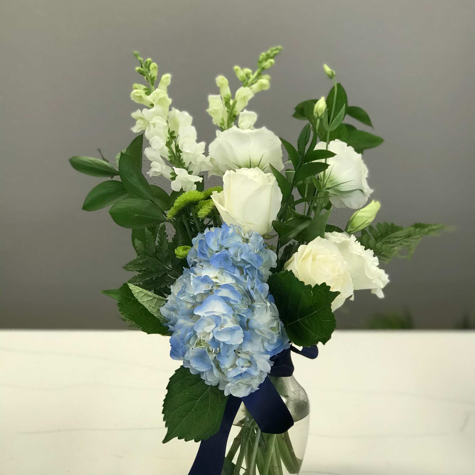 Shades of green and ivory float above a center stage blue hydrangea.