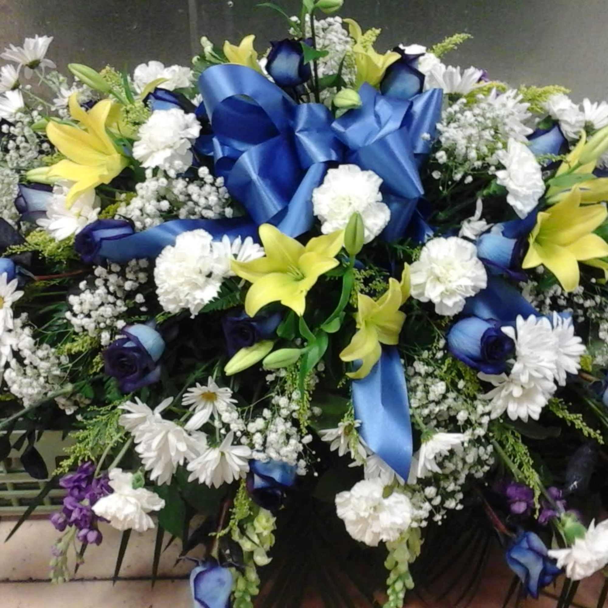 This casket make with blue roses, yellow lilies and white carnation 