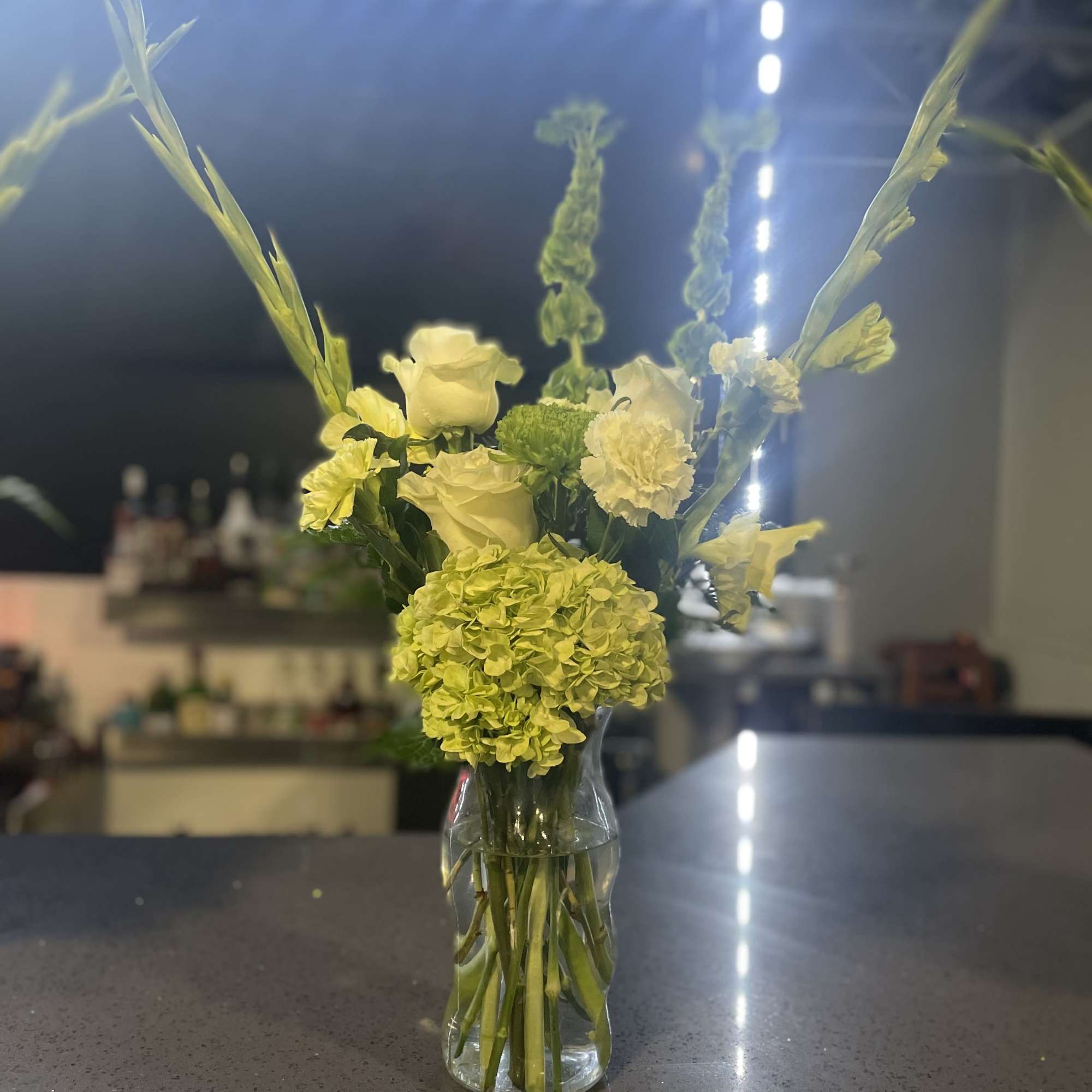 A arrangement filled with green roses, hydrangeas, gladiolus and other green mixed