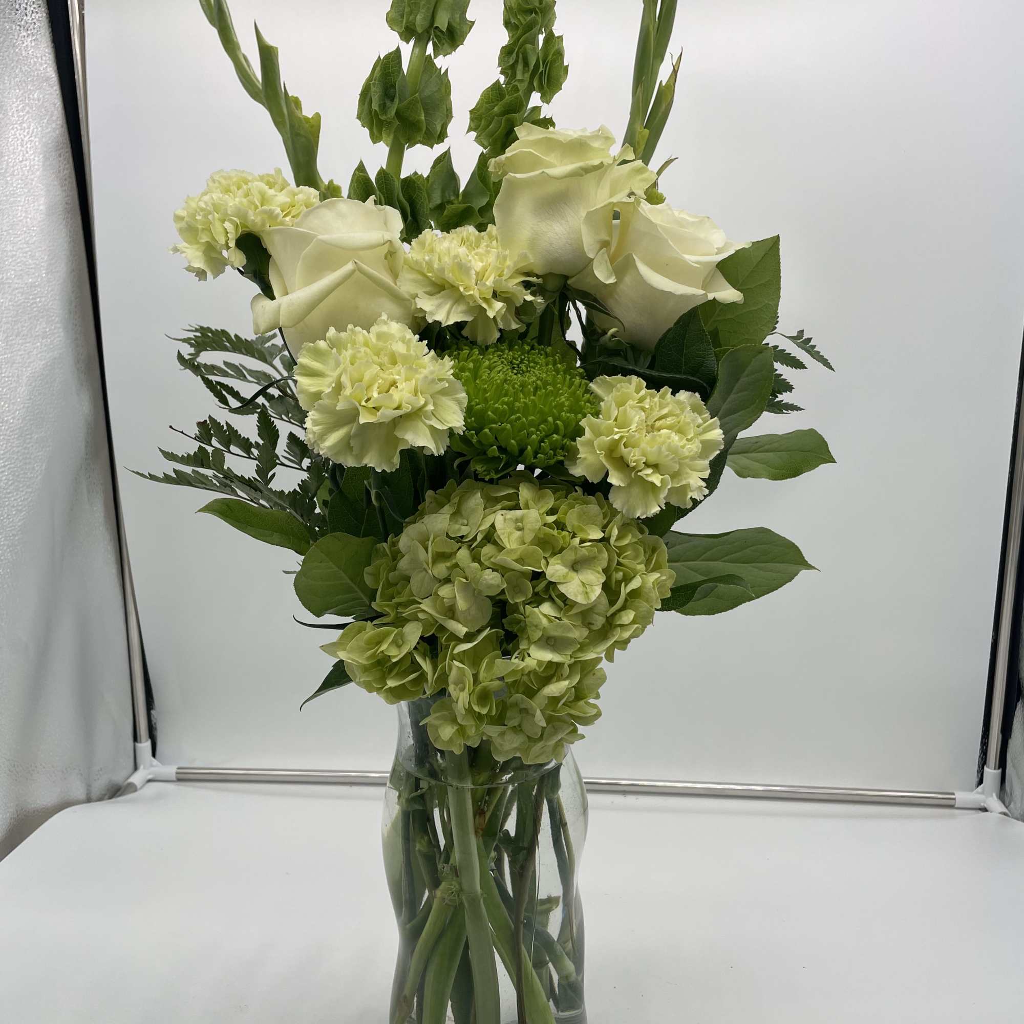 A arrangement filled with green roses, hydrangeas, gladiolus and other green mixed