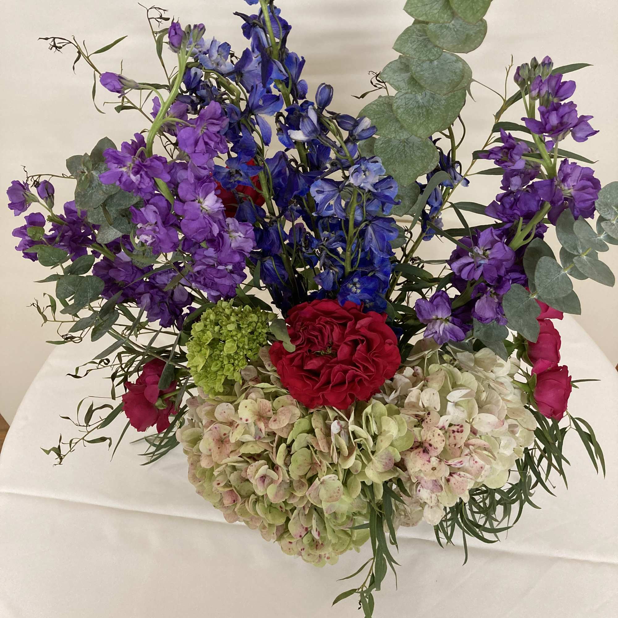 Pink hydrangea, red garden roses, delphinium, purple stock