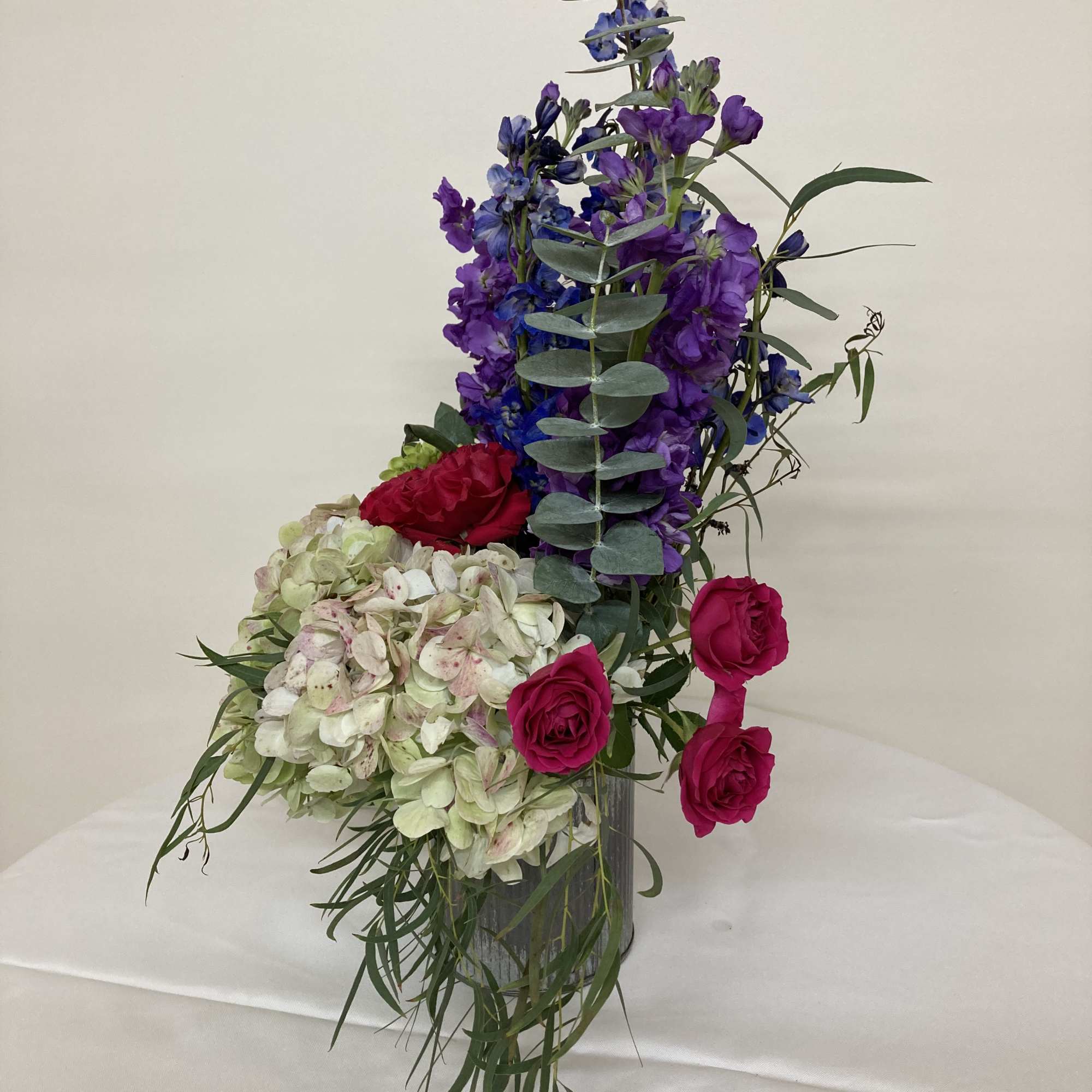 Pink hydrangea, red garden roses, delphinium, purple stock