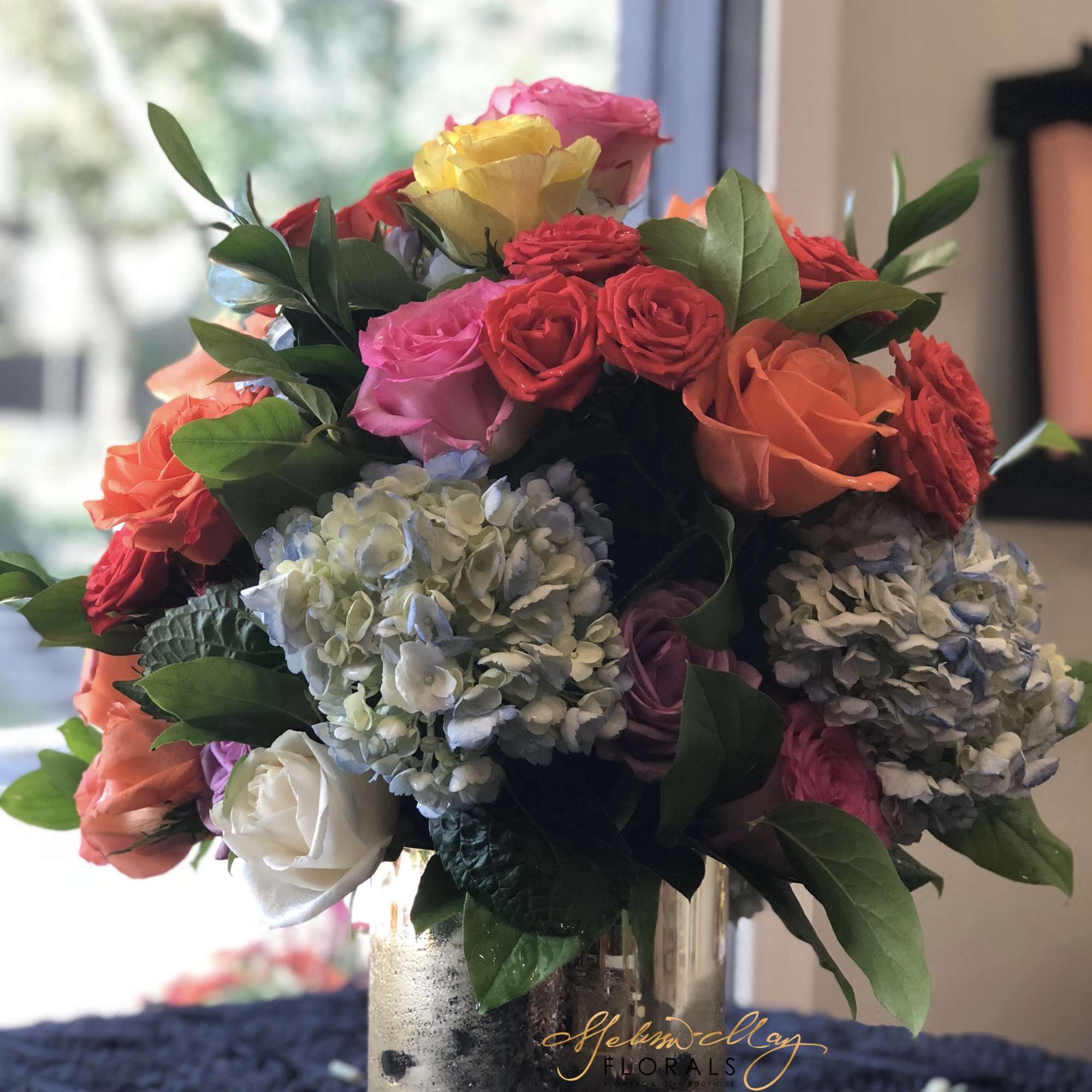An all-around arrangement with an assortment of roses and hydrangeas with assorted