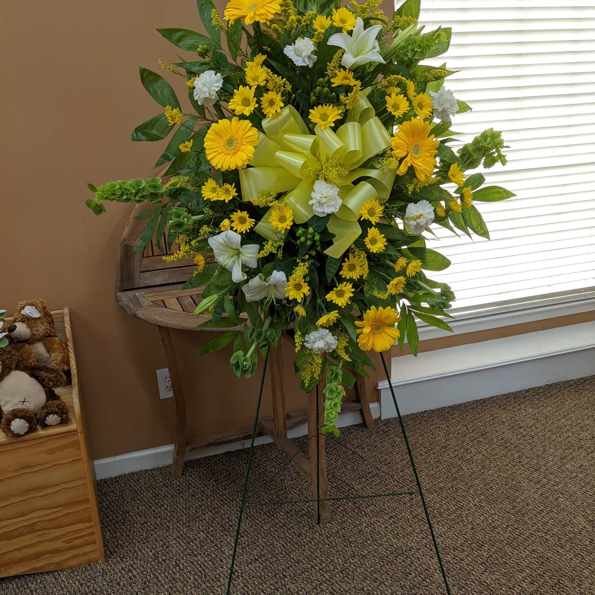 Standing spray with mix of yellow and white flowers.