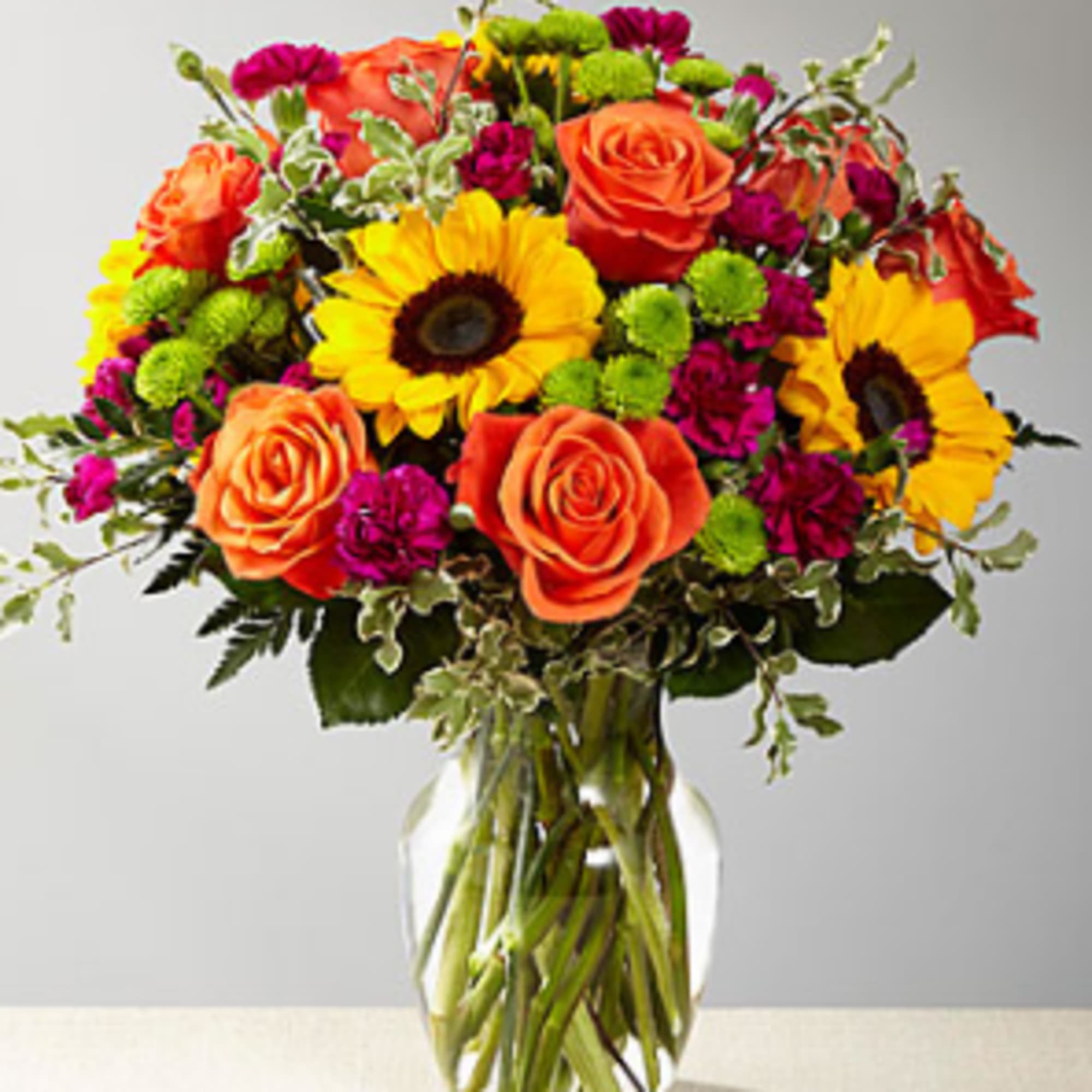 Our floral professionals weave together a blend of orange roses, sunflowers, violet