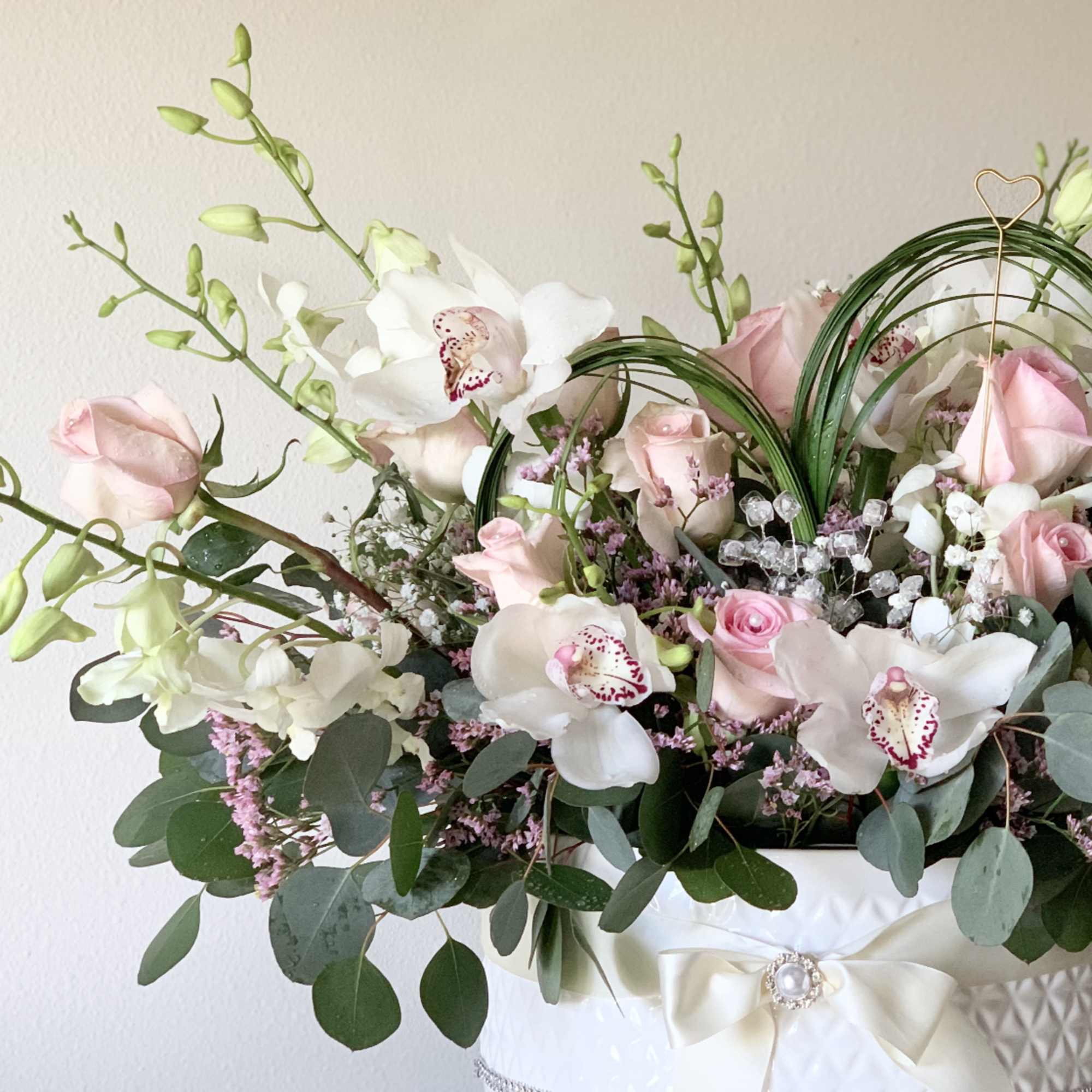 Fresh flowers in the ceramic vase, decorated with a silk ribbon, pearls