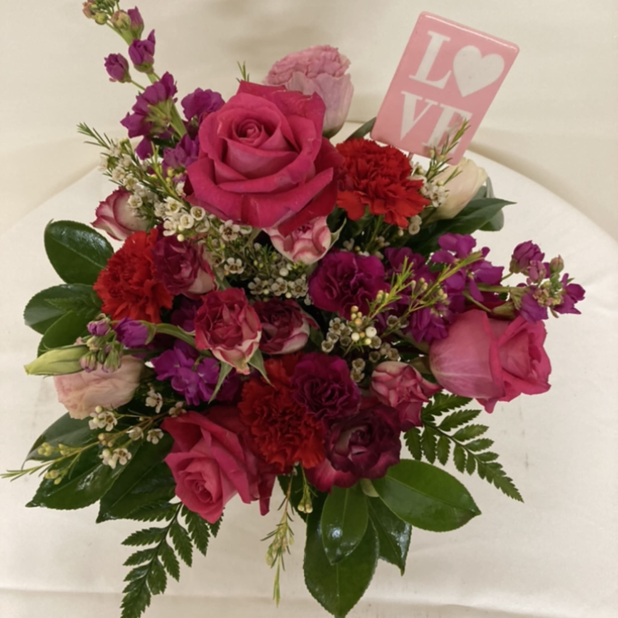 Roses, stock, and carnations with a LOVE placard