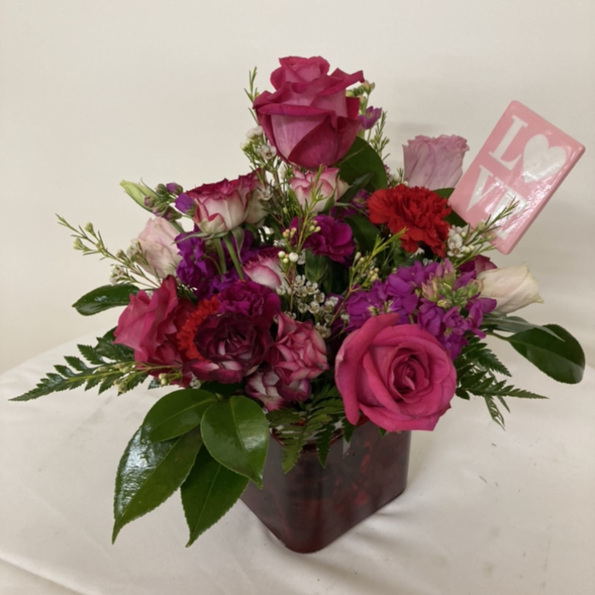 Roses, stock, and carnations with a LOVE placard