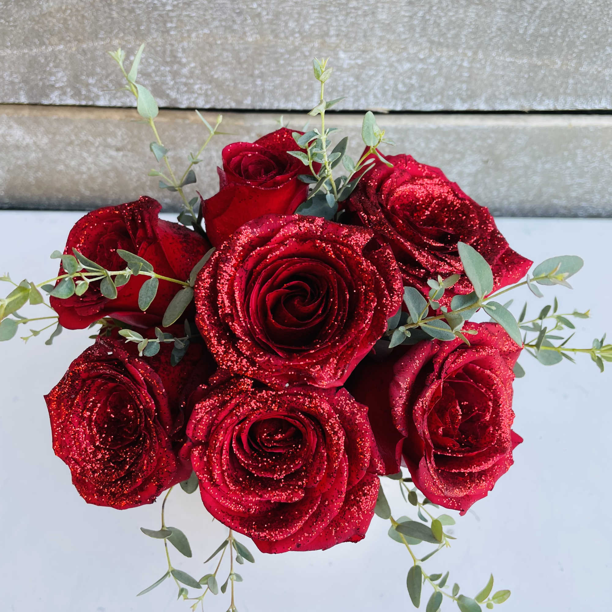 A half dozen red roses glittered in a fashionable bud vase with A half dozen red roses glittered in a fashionable bud vase with