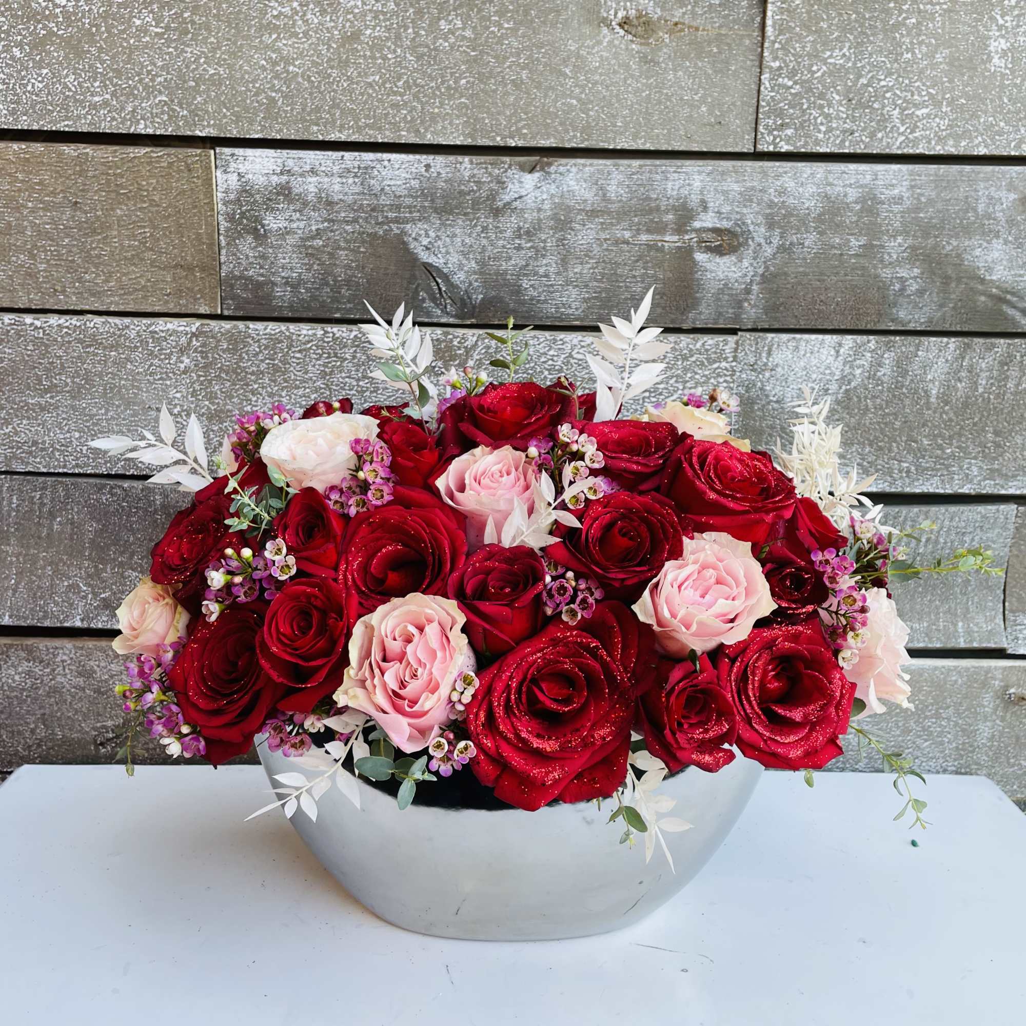 Red and pink roses in silver container with waxflower and white dried Red and pink roses in silver container with waxflower and white dried