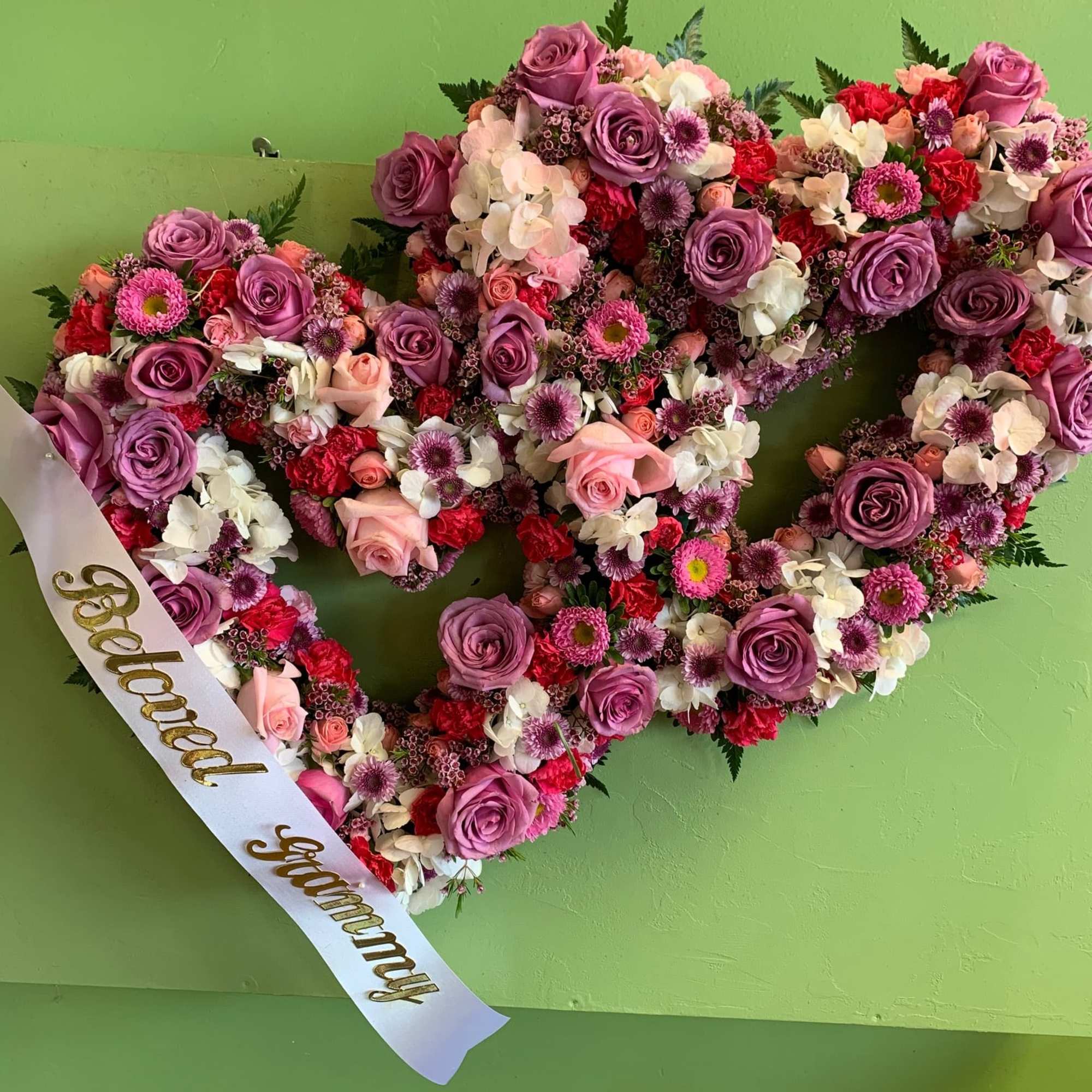 Two hearts meld as one in this beautiful funeral wreath meant to