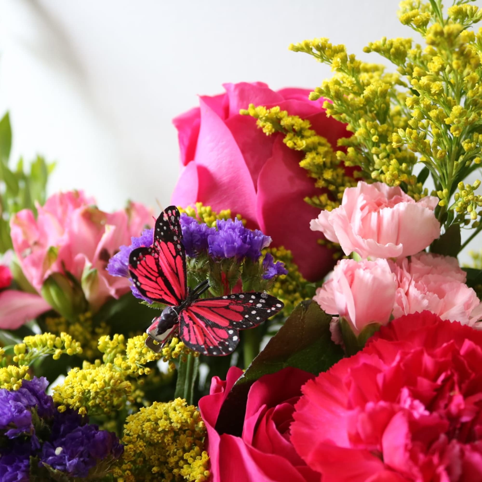 A bright, beautiul basket arrangment with hot pink roses, sunflowers, carnations, cymbidium