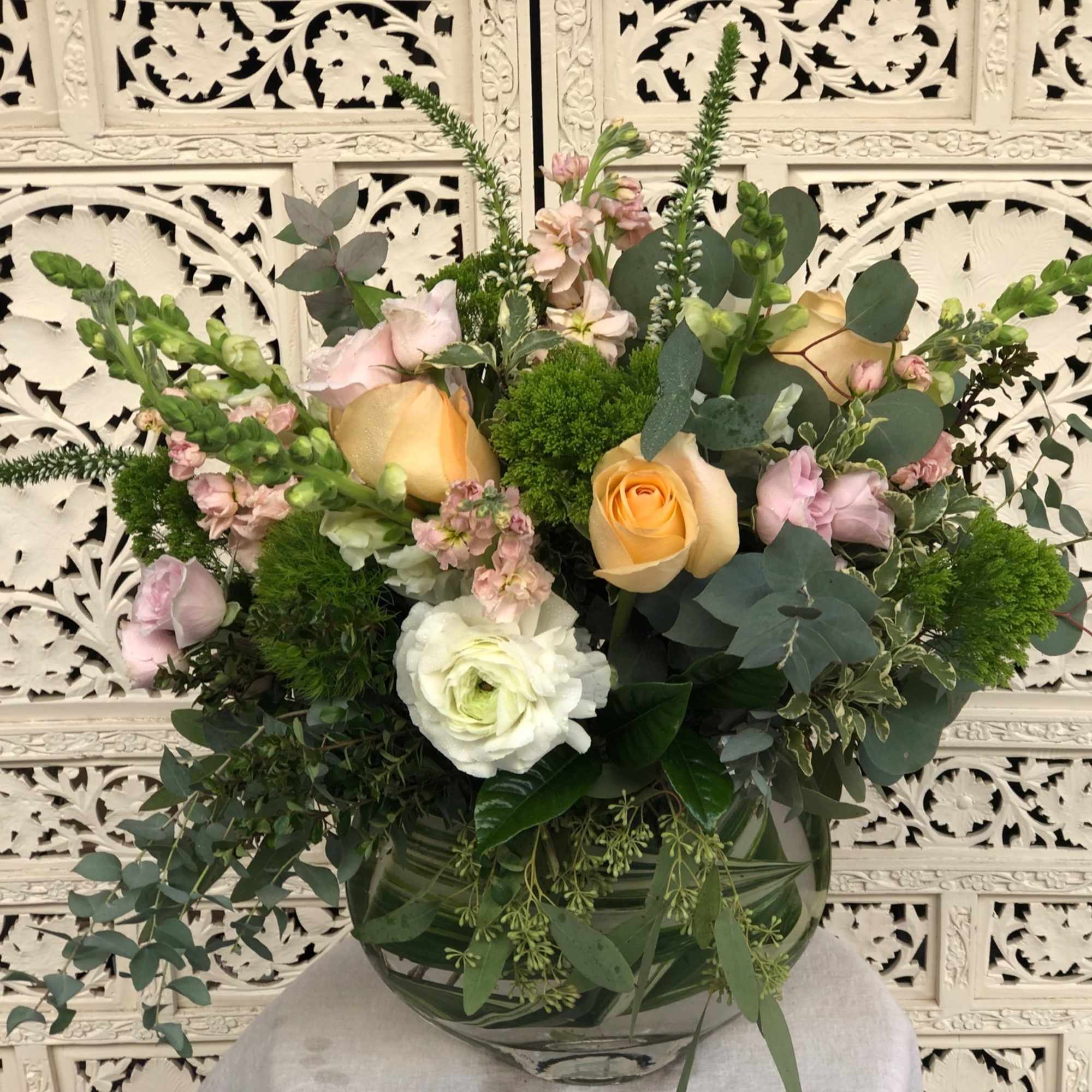 Lush, sherbet colored arrangement in unique eclipse shaped vase that&#039;s lined by