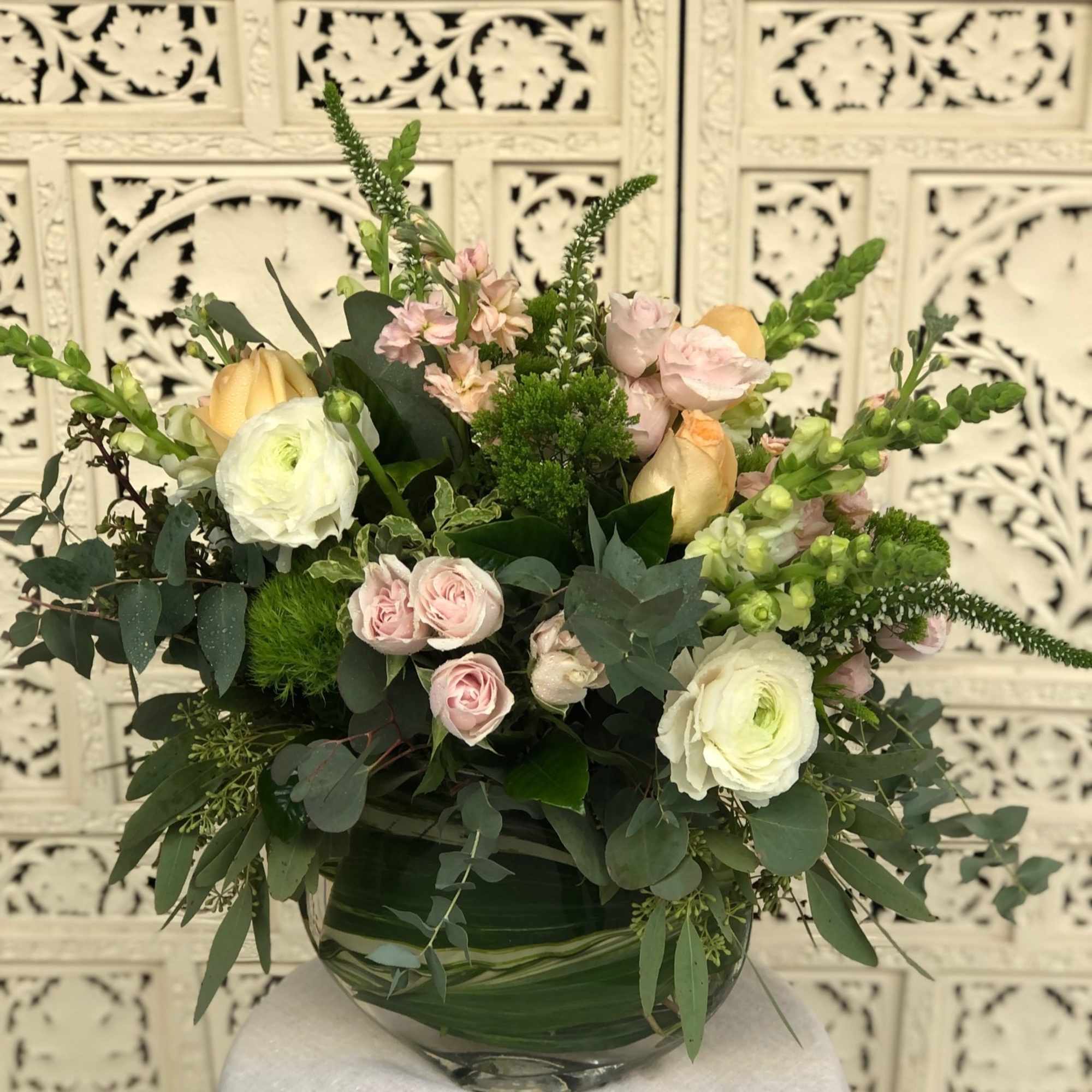 Lush, sherbet colored arrangement in unique eclipse shaped vase that&#039;s lined by