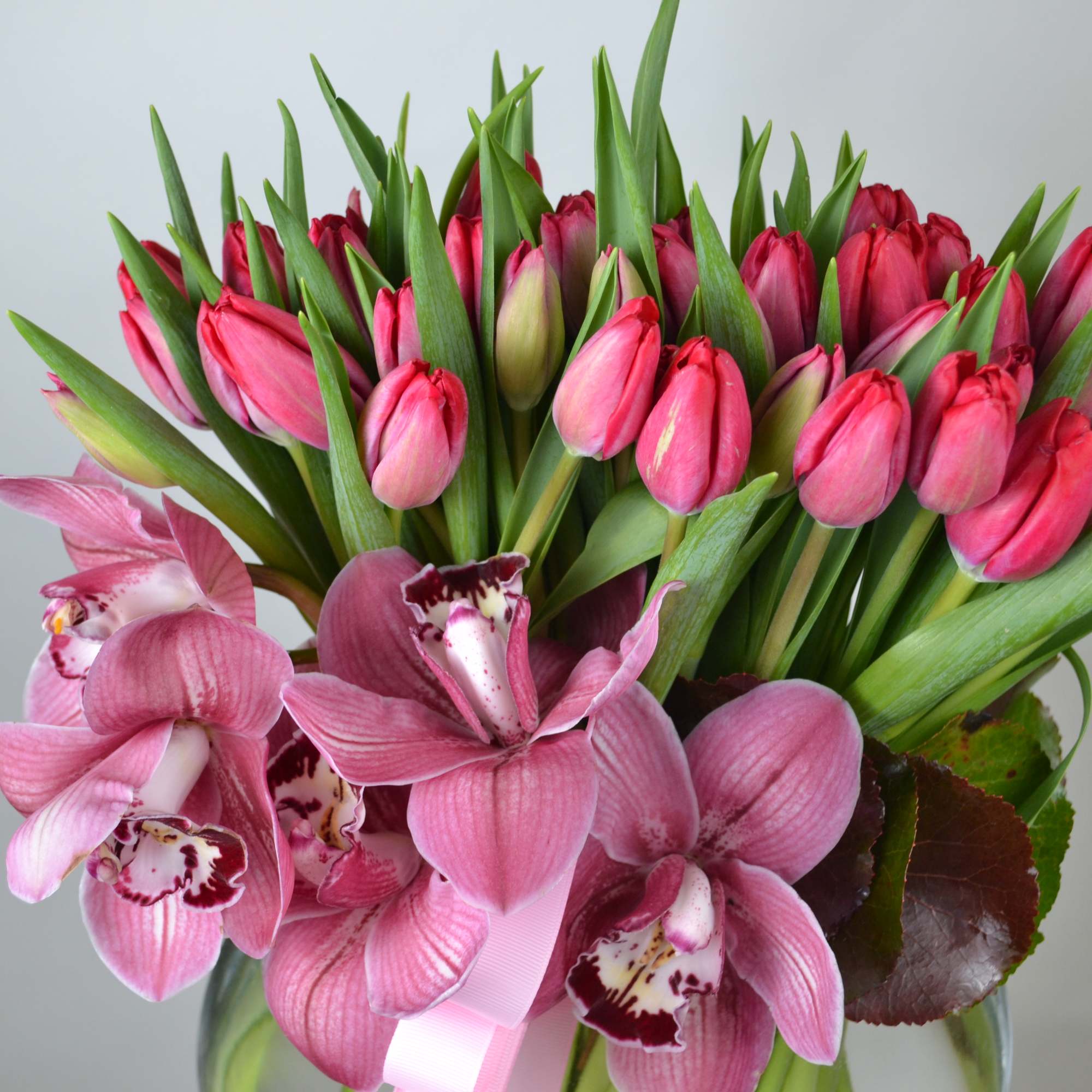 Beatiful Red Tulips. with red cymbidium in half moon shape vase