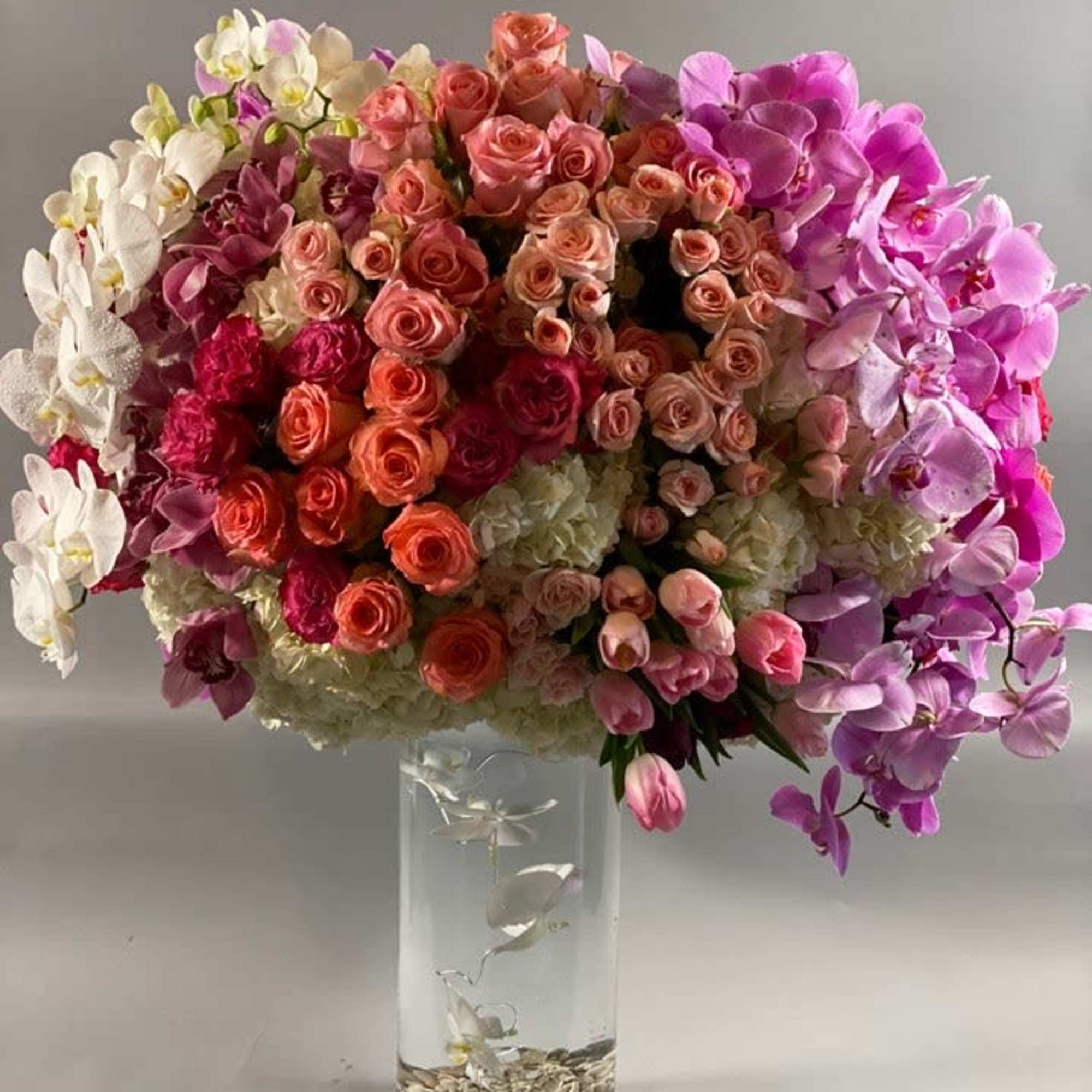 A grandiose and opulent display of coral, purple, and pink blooms of