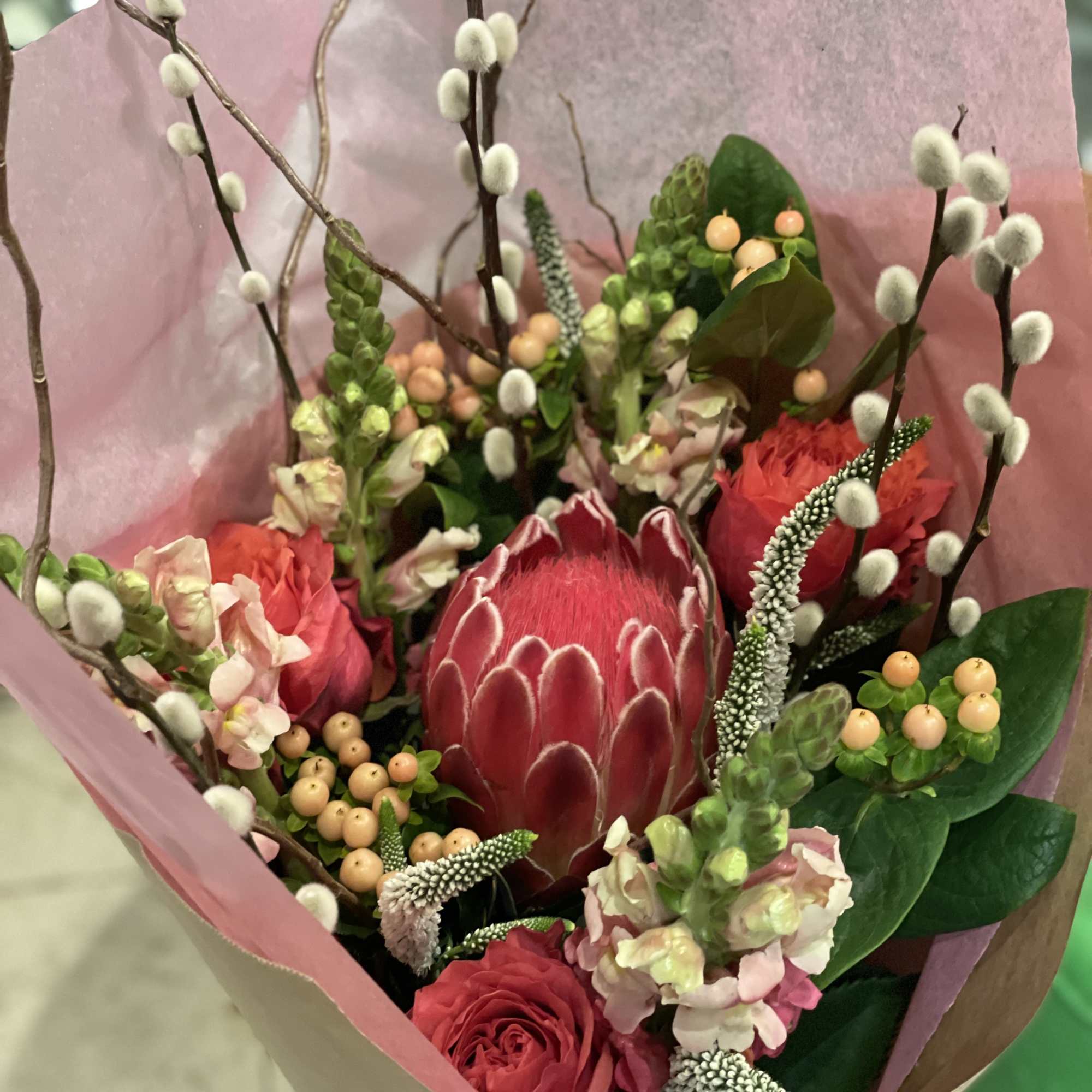 Exquisite custom bouquet with exotic raspberry protea, garden roses, willow, and snapdragons.