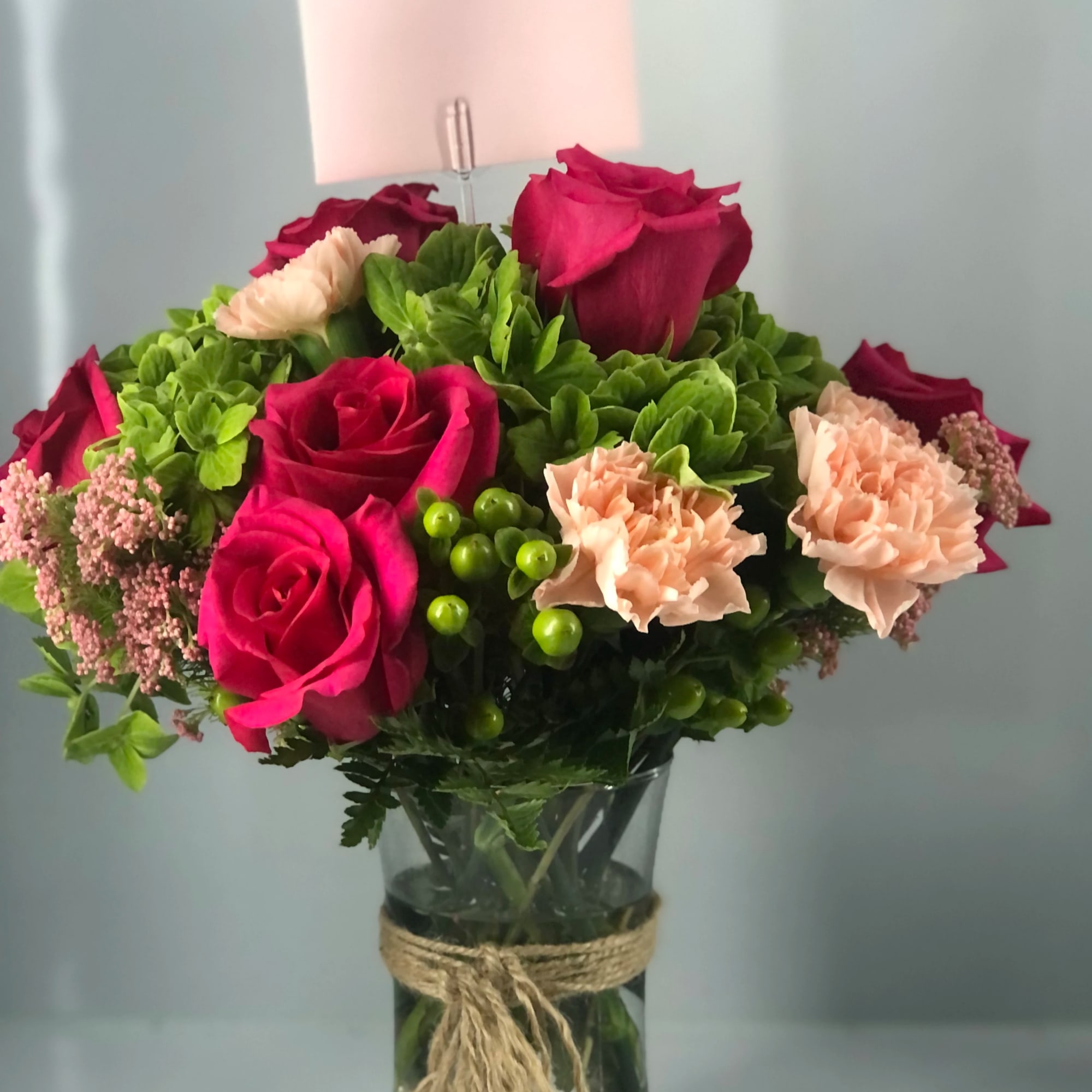 Light foliage,  mostly beautiful blooms fill this glass vase 