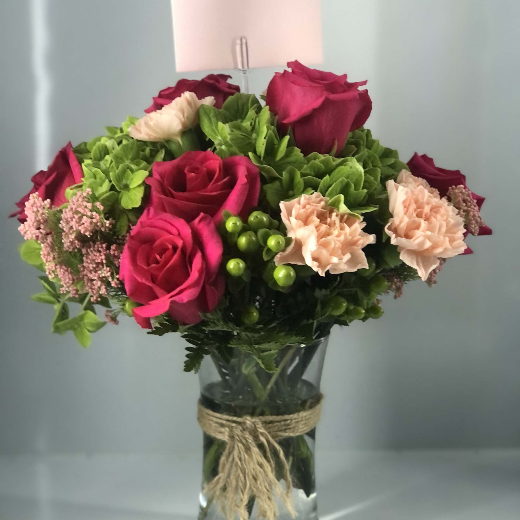 Light foliage,  mostly beautiful blooms fill this glass vase 