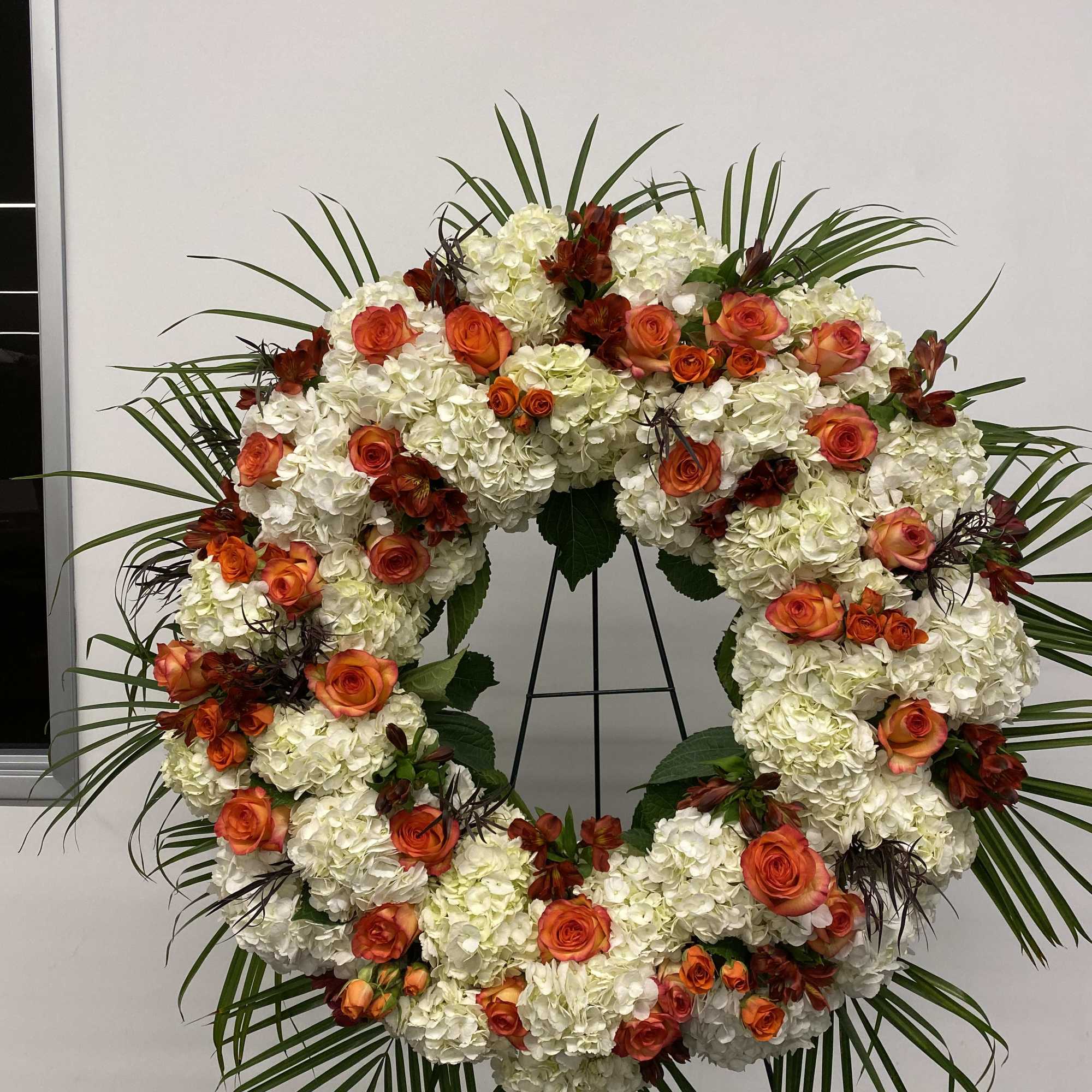 Beautiful white and orange round spray on a tall easel.