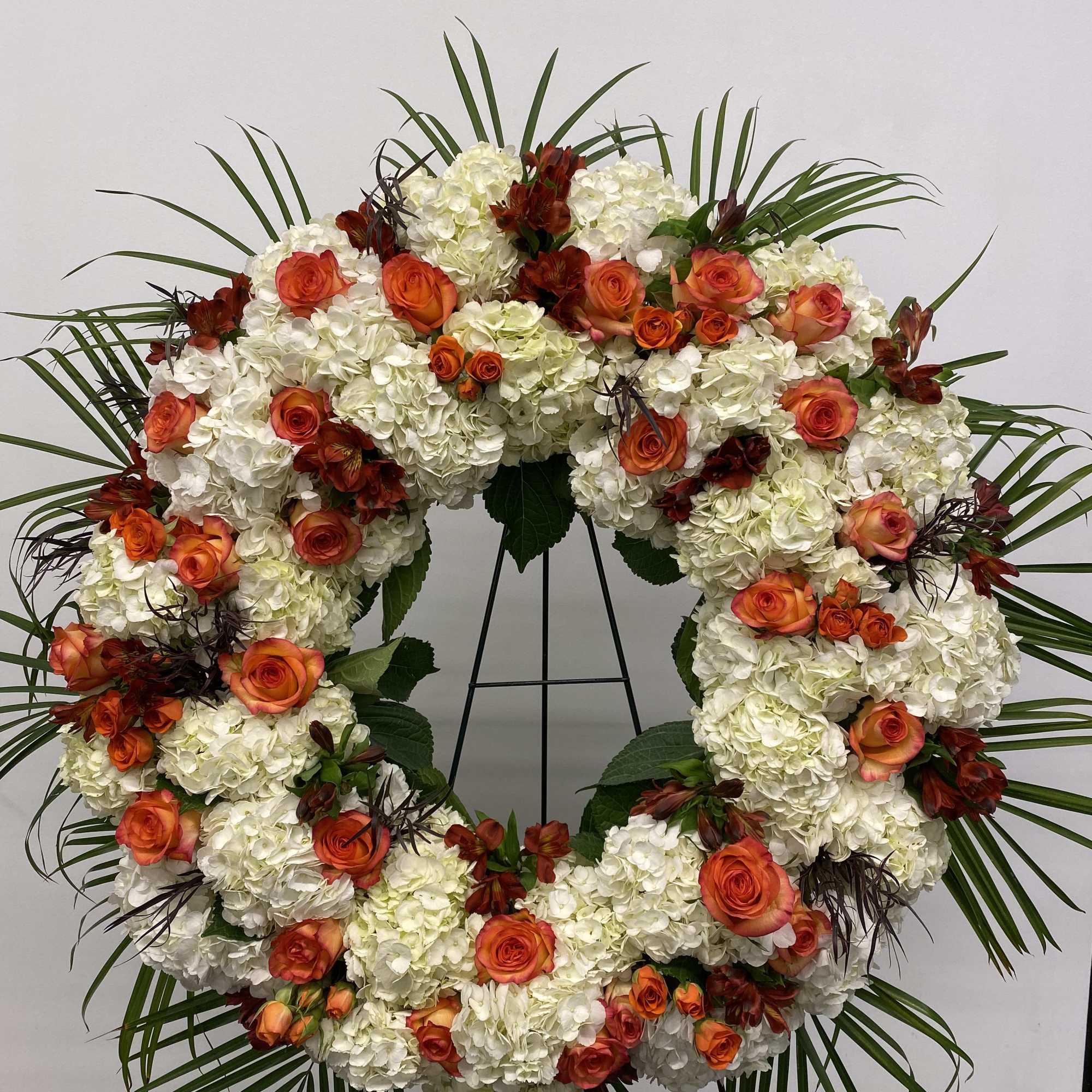 Beautiful white and orange round spray on a tall easel.