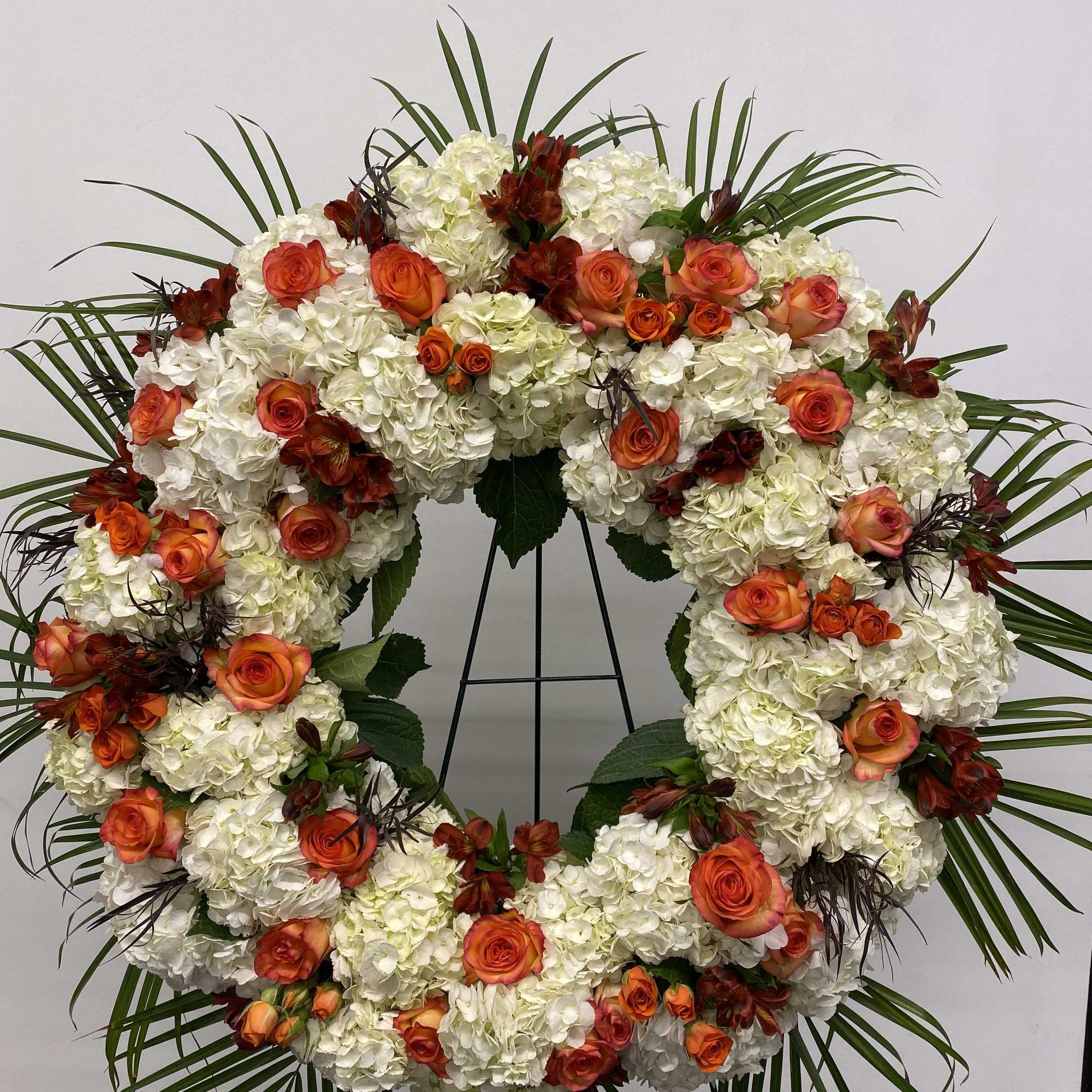 Beautiful white and orange round spray on a tall easel.