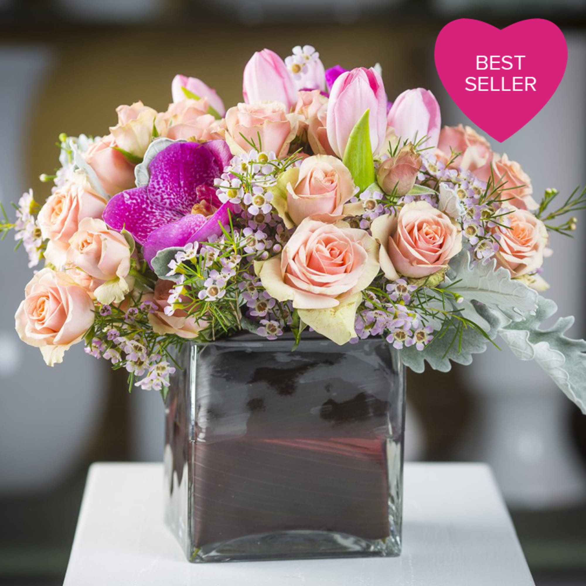 Spray roses, tulips, wax, dusty miller, &amp; vanda orchids in a leaf