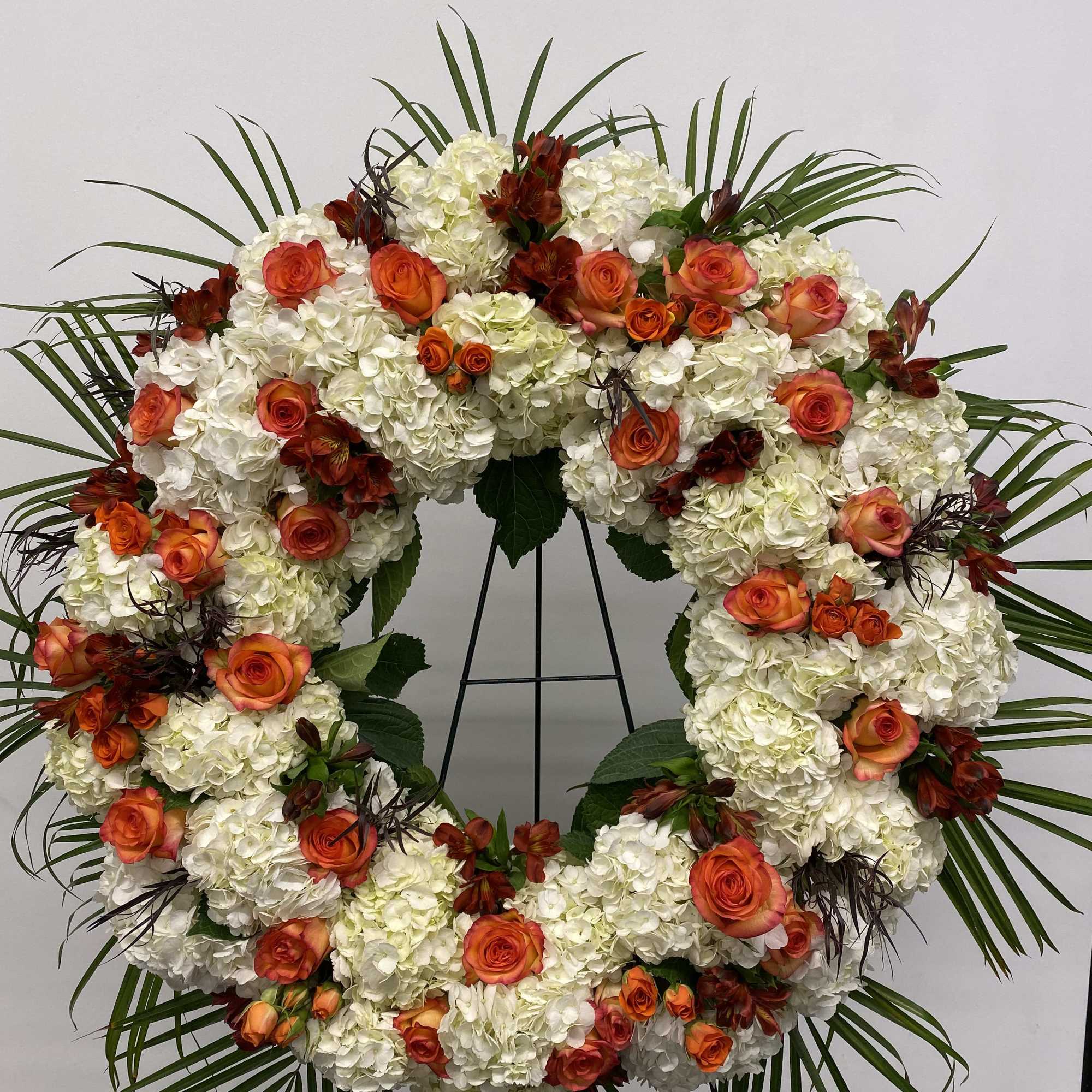 Beautiful white and orange round spray on a tall easel.