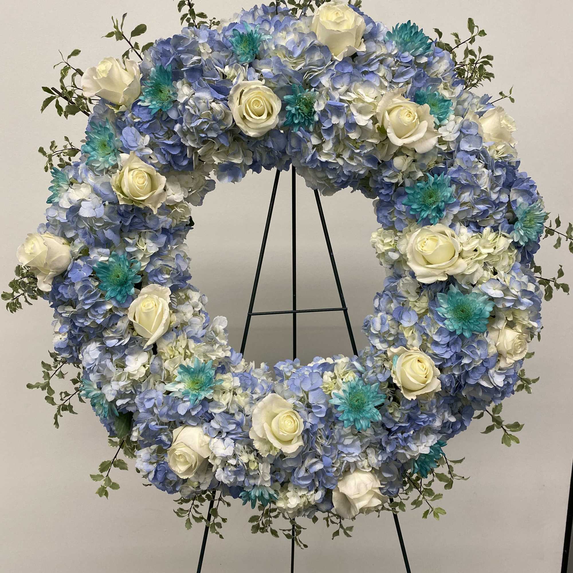 Very large wreath of hydrangeas, roses and greenery. Colors are Light blue
