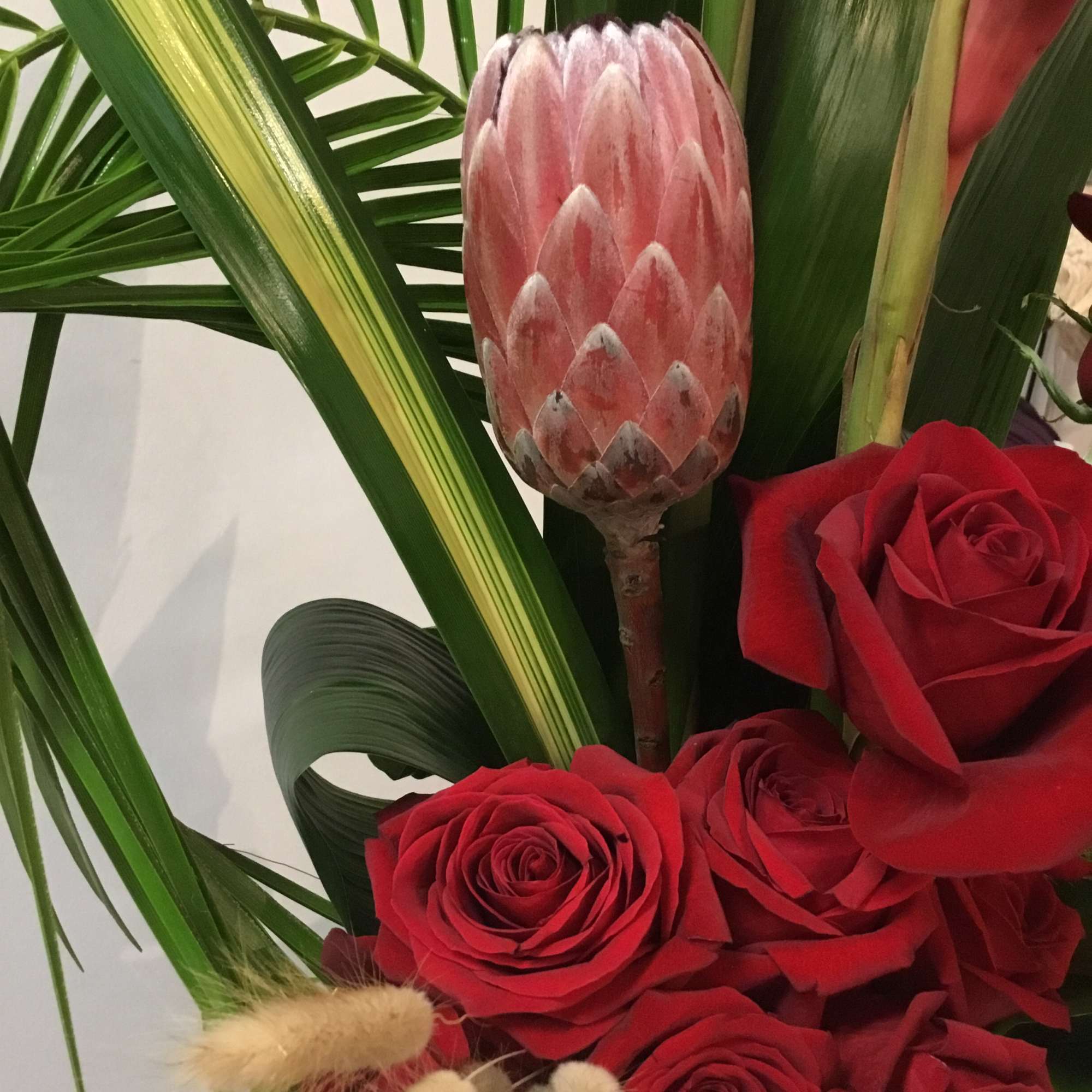 A tropical work of art floral arrangement with protea and roses