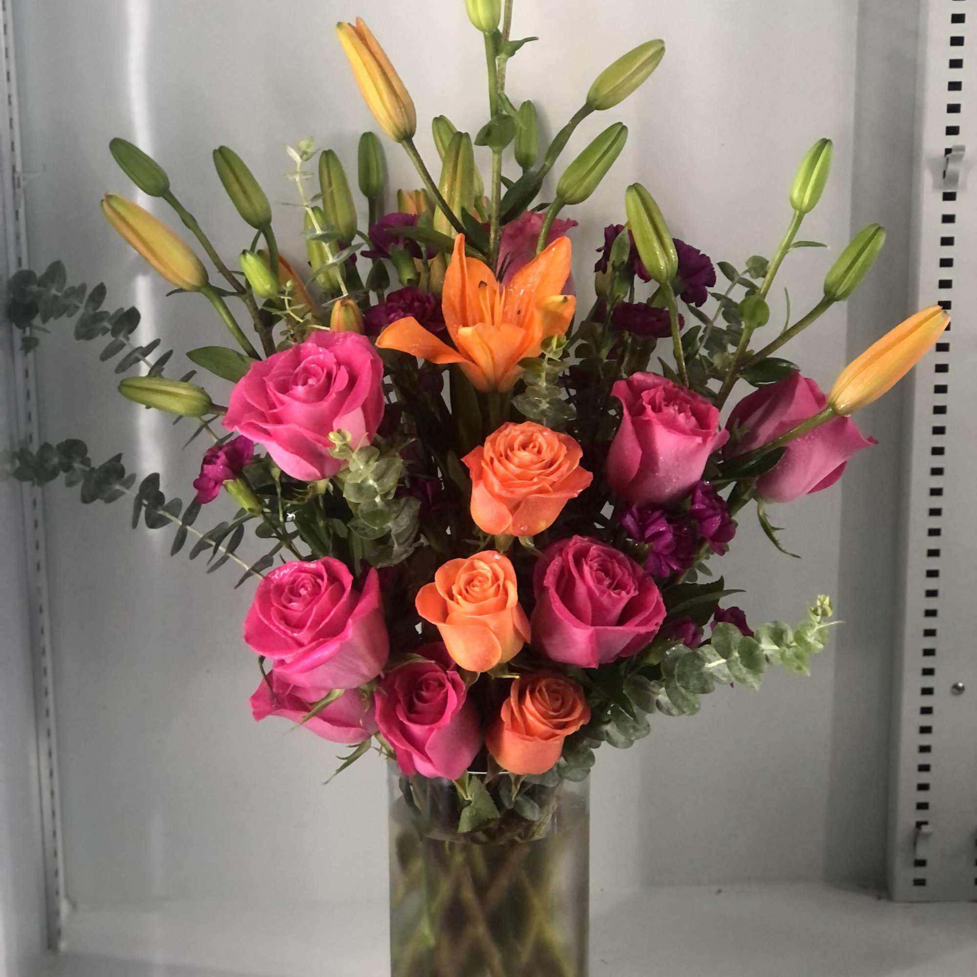 Hot pink roses ,orange roses and orange lilies  delicately arranged, might