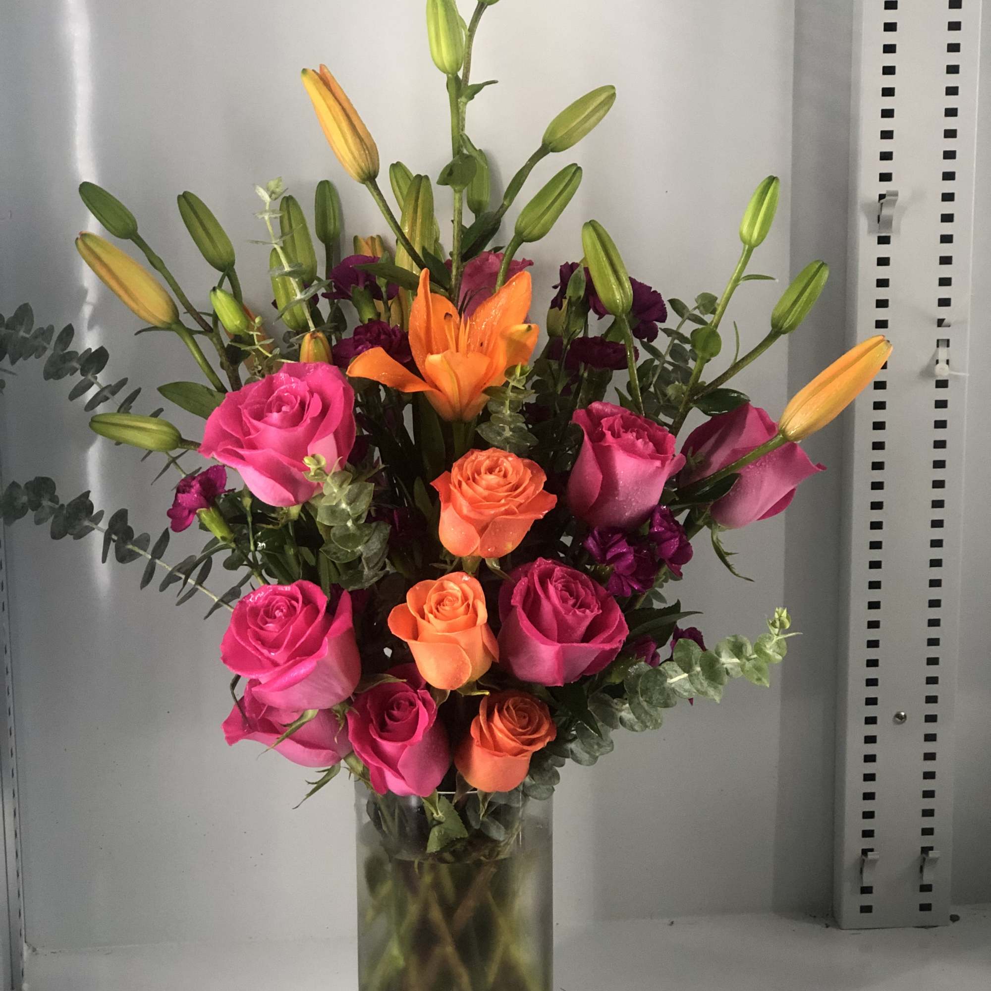 Hot pink roses ,orange roses and orange lilies  delicately arranged, might