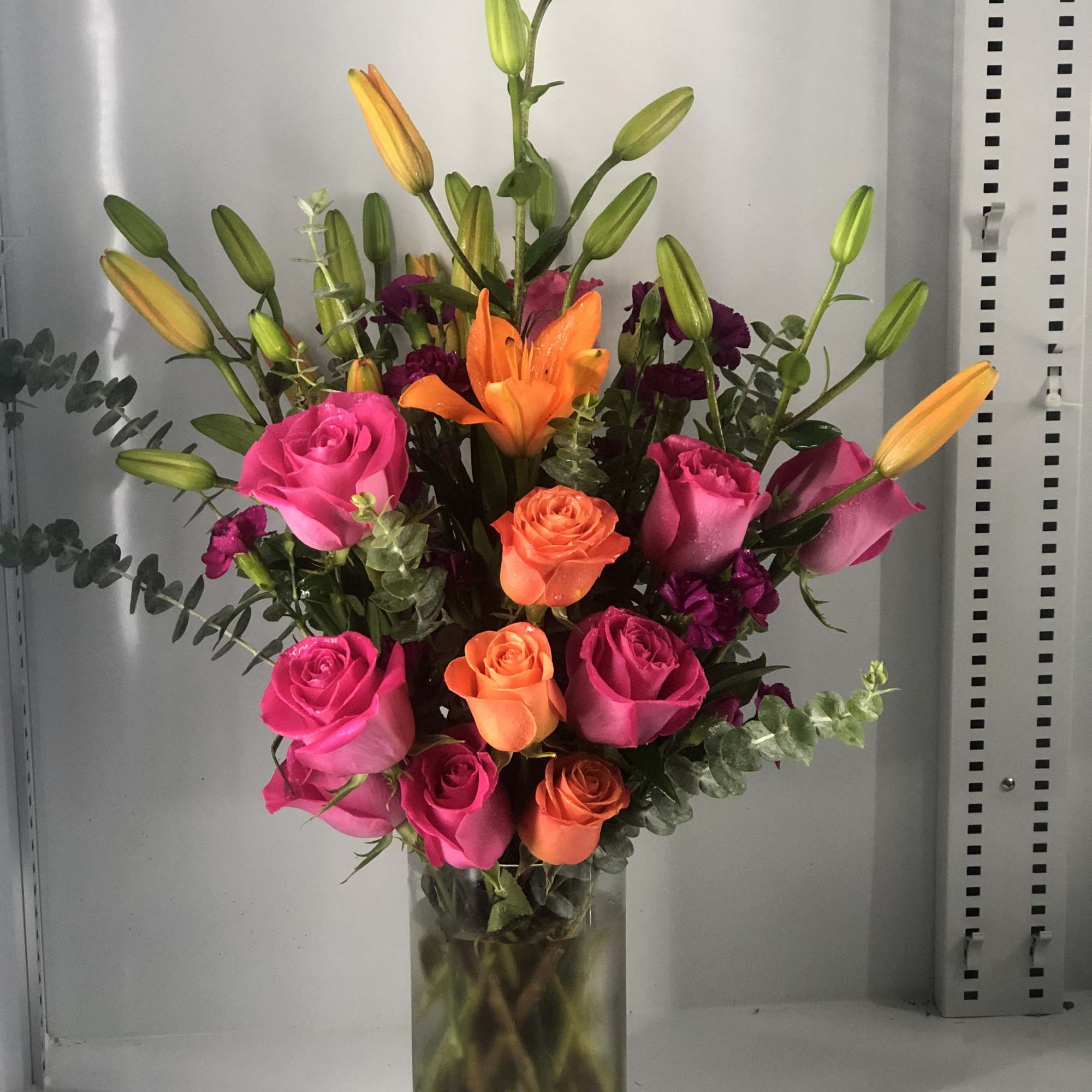 Hot pink roses ,orange roses and orange lilies  delicately arranged, might