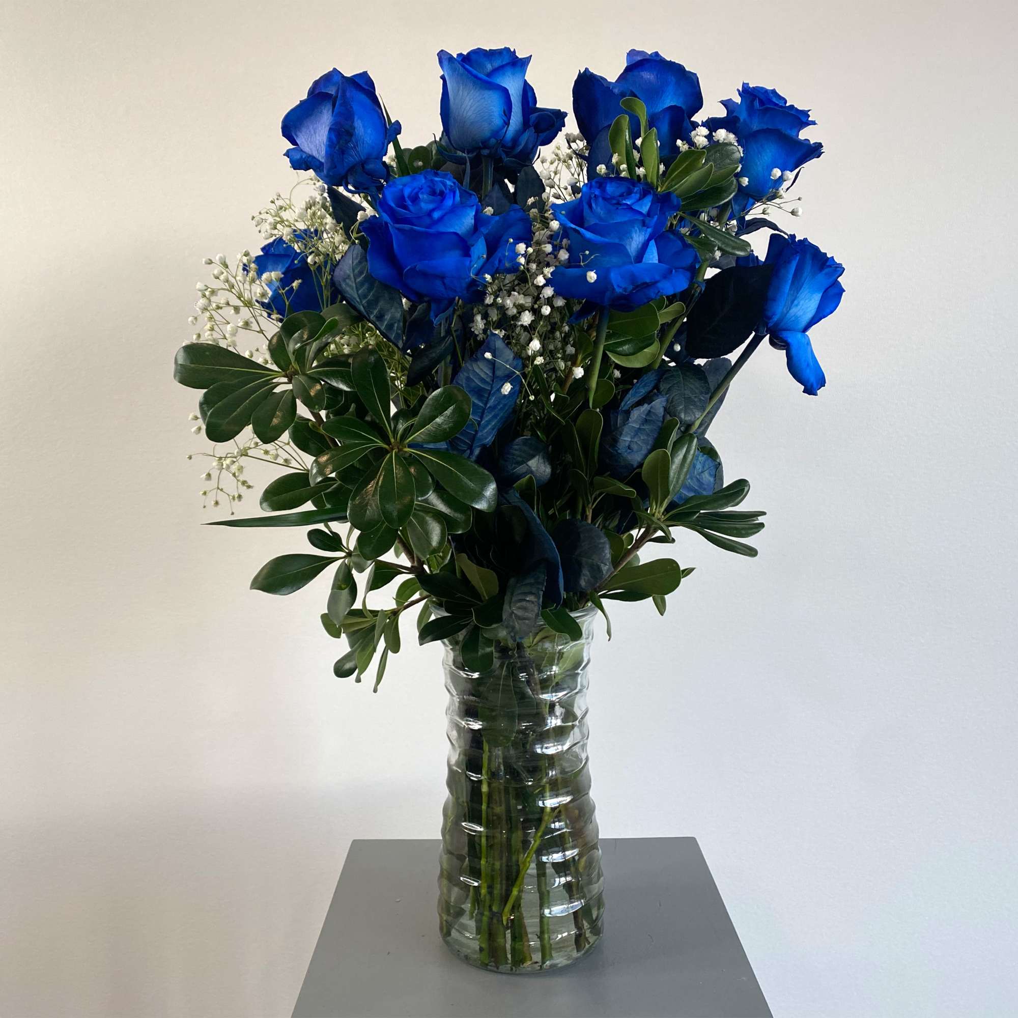 1 dozen blue tinted roses with greens and baby breath arranged in