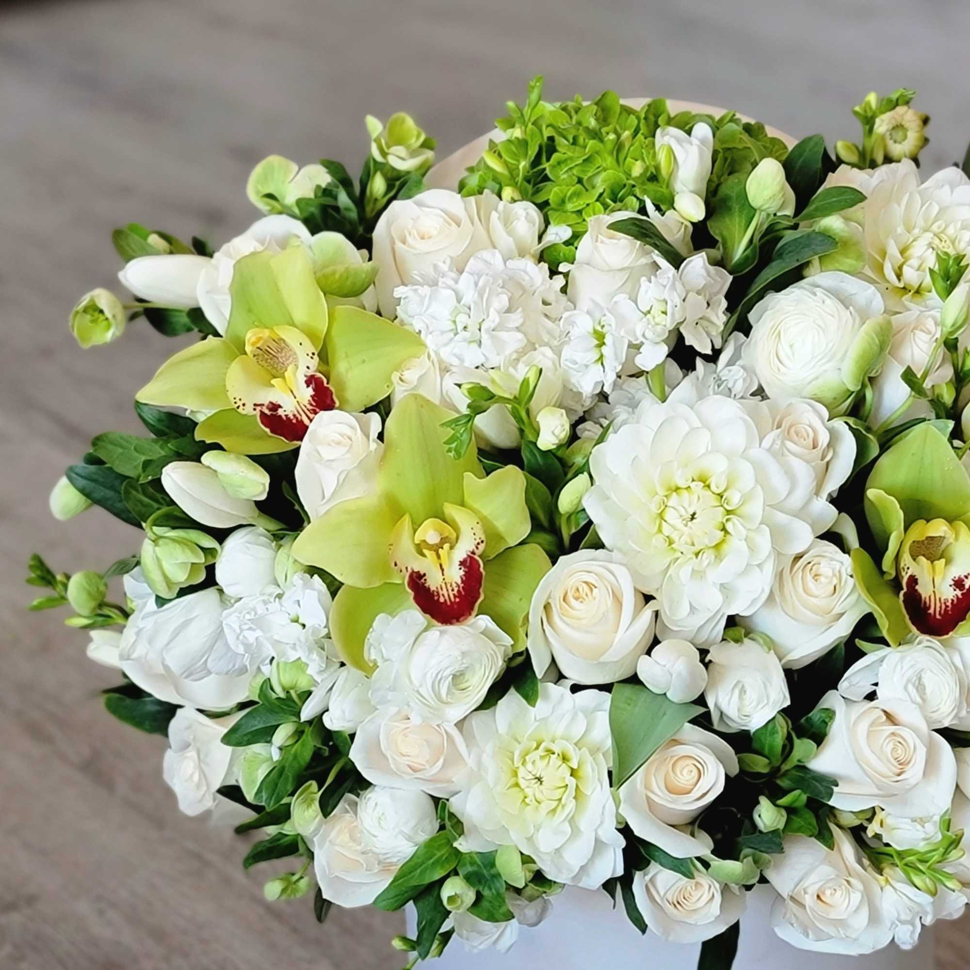 The composition with white dahlias, rununculi and green orchids looks fresh and