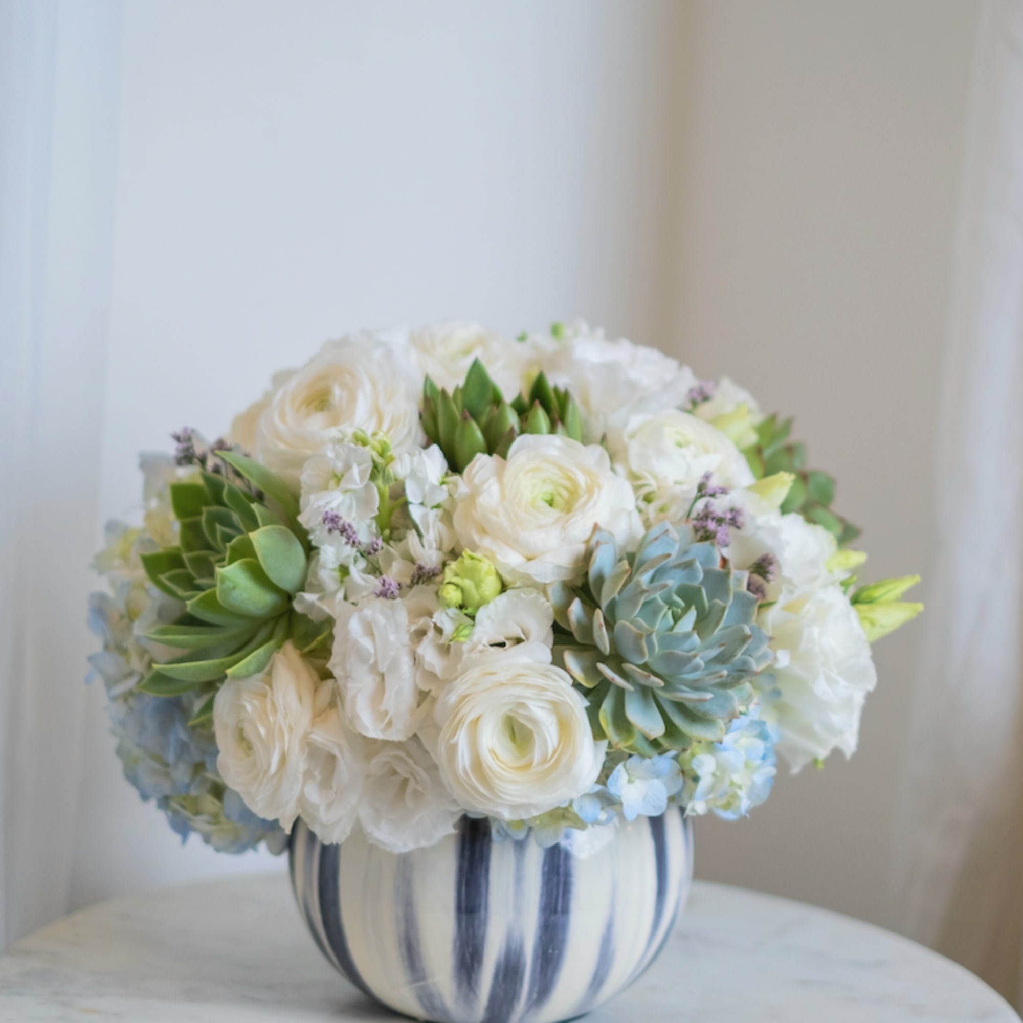The arrangement with delicate white rununculuses and elegant succulents looks interesting and